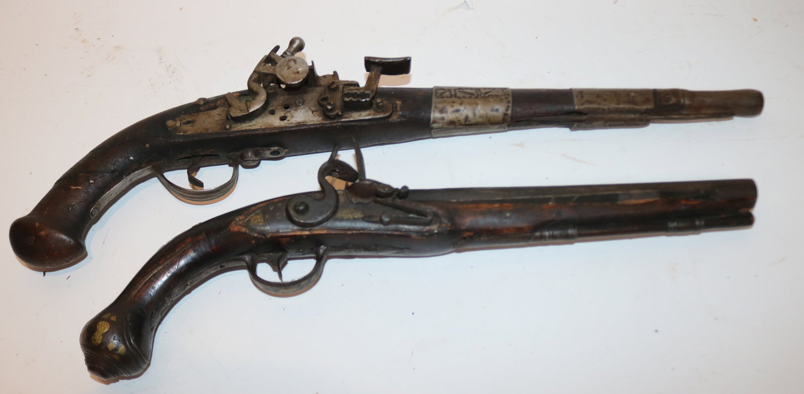 2 PERSIAN FLINT LOCK PISTOLS, 1 WITH BRASS INLAY,: BOTH SHOW SOME DAMAGE TO STOCKS, 16 1/2" - 20 1/4" L, POSSIBLY WORKING CONDITION
