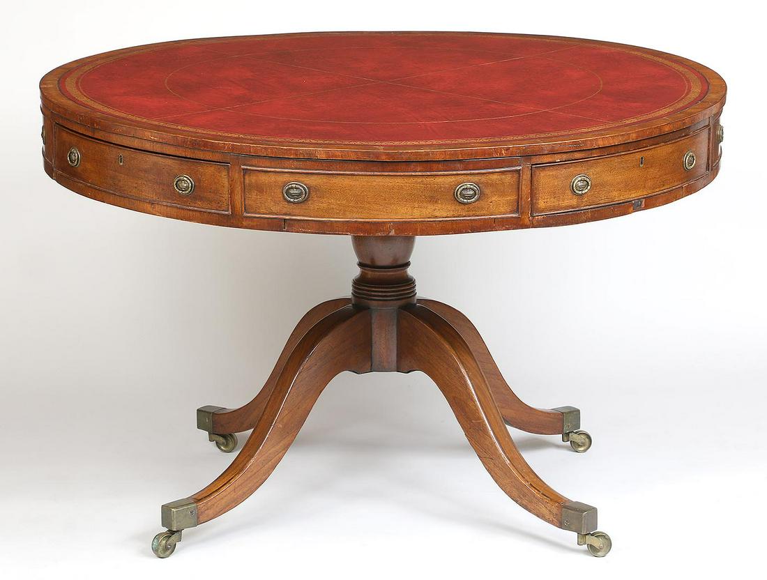 19th century English leather top drum table: 19th century English leather top drum table with tooled inset red leather top, four opposing drawers and four false drawers, set on quatrefoil base ending on casters. Veneer losses, one pull missing.