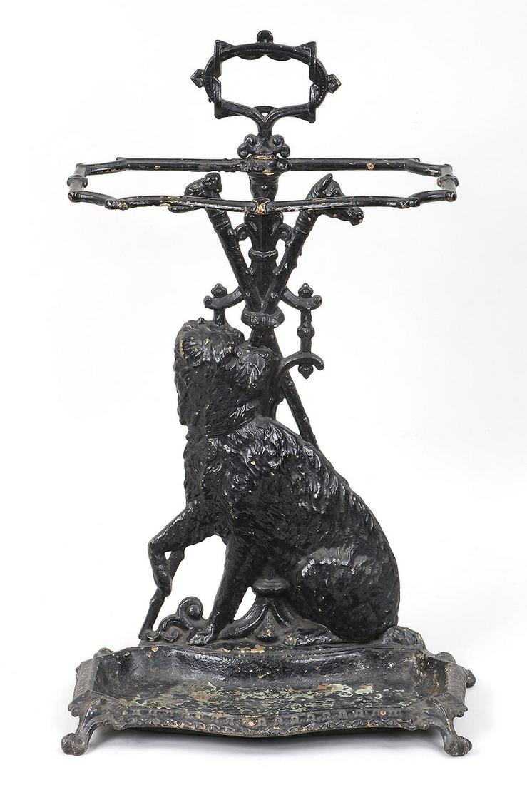 Cast iron handled umbrella stand: Cast iron handled umbrella stand with relief depicting dog and canes, on four paw feet. 25''h, 15''w, 8-3/4''d.
