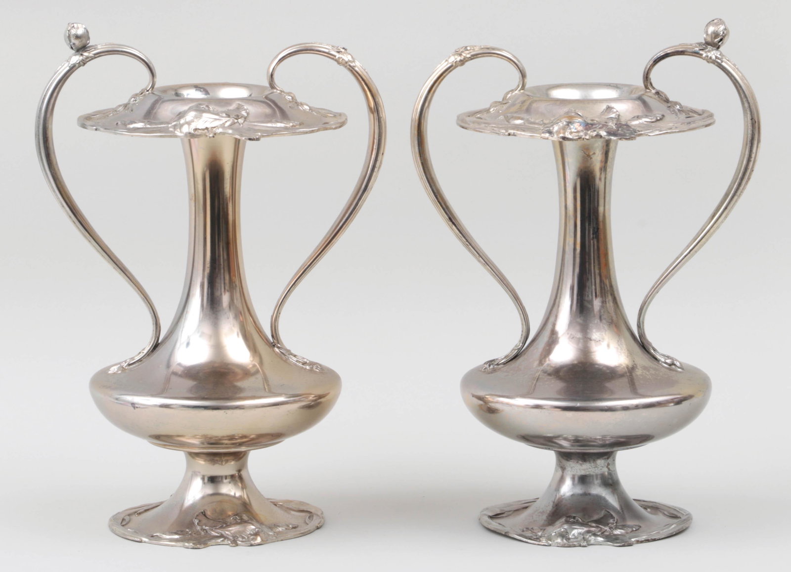 Pair of Art Nouveau silverplate footed vases: Pair of Art Nouveau silverplate footed vases with handles and foliate relief. Plate loss. 14-5/8''h.