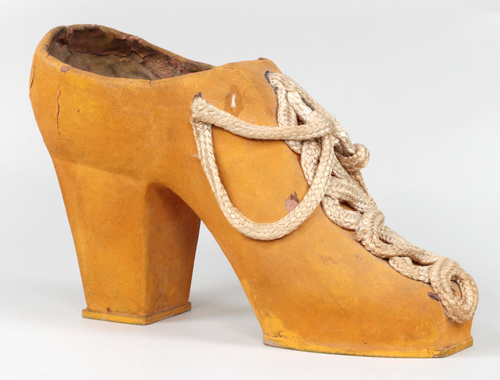 Large Folk Art paper mache high heeled shoe: Large Folk Art paper mache high heeled shoe in yellow with rope laces and wooden sole. Wear. 10-1/4''h, 6-1/4''h, 16-1/4''d.