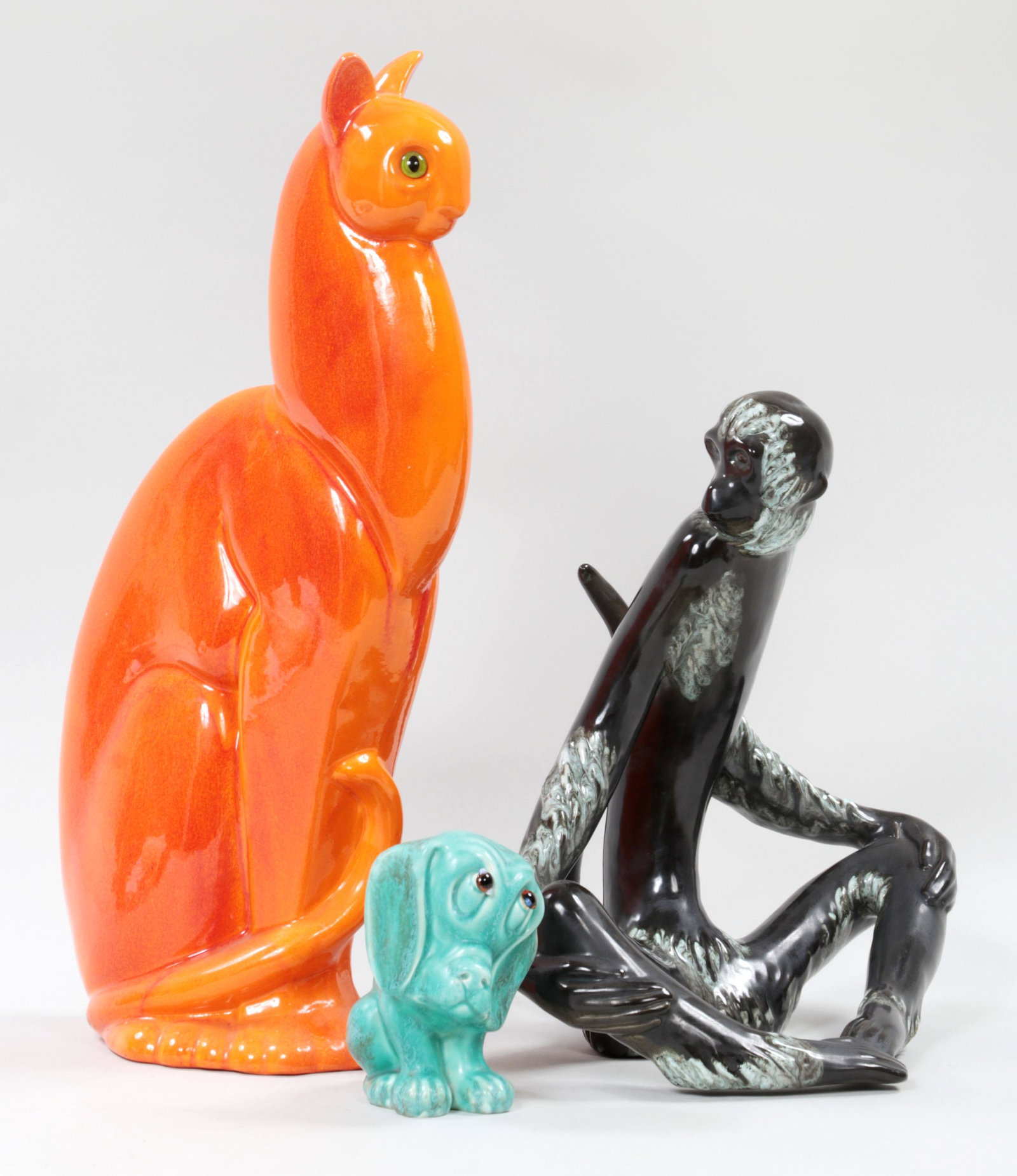 Group of (3) porcelain animals: Group of (3) porcelain animals, to include: Crown Devon puppy; Royal Haeger pottery cat in orange; and sitting monkey. Hairlines and minor glaze gap to cat. Largest 20-5/8''h, 6-1/4''w, 10-1/2''d.
