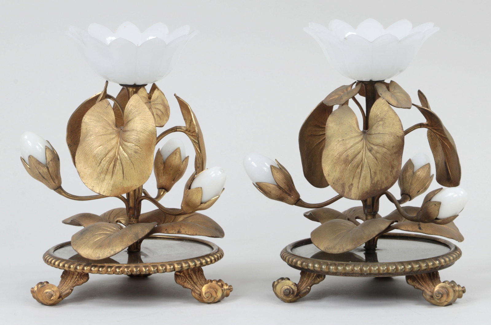 Pair of French bronze garnitures: Pair of French bronze garnitures with glass flowers and buds, and mirrored bases on three scrolled feet. Wear to gilding. 11-1/2''h.