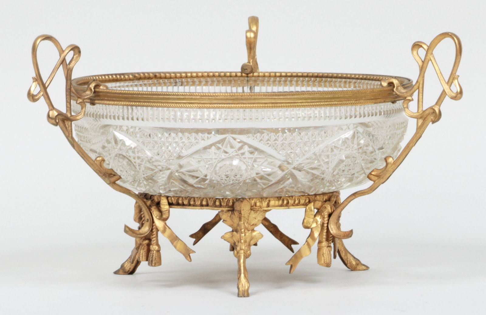 Cut crystal bowl: Cut crystal bowl with gilt bronze mount on three hoof feet. Chips and flakes. 7-3/4''h, 13''w, 10-3/8''dia.