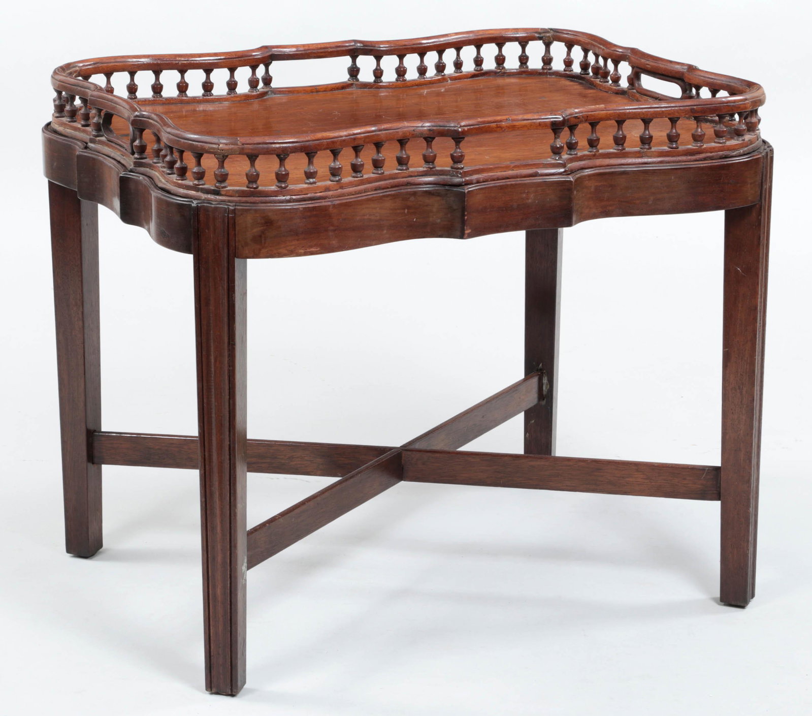 19th century shaped butler's tray: 19th century mahogany shaped butler's tray with gallery, set on conforming stand with cross stretcher. Repairs and losses. 21''h, 25-1/2''w, 19-1/4''d.