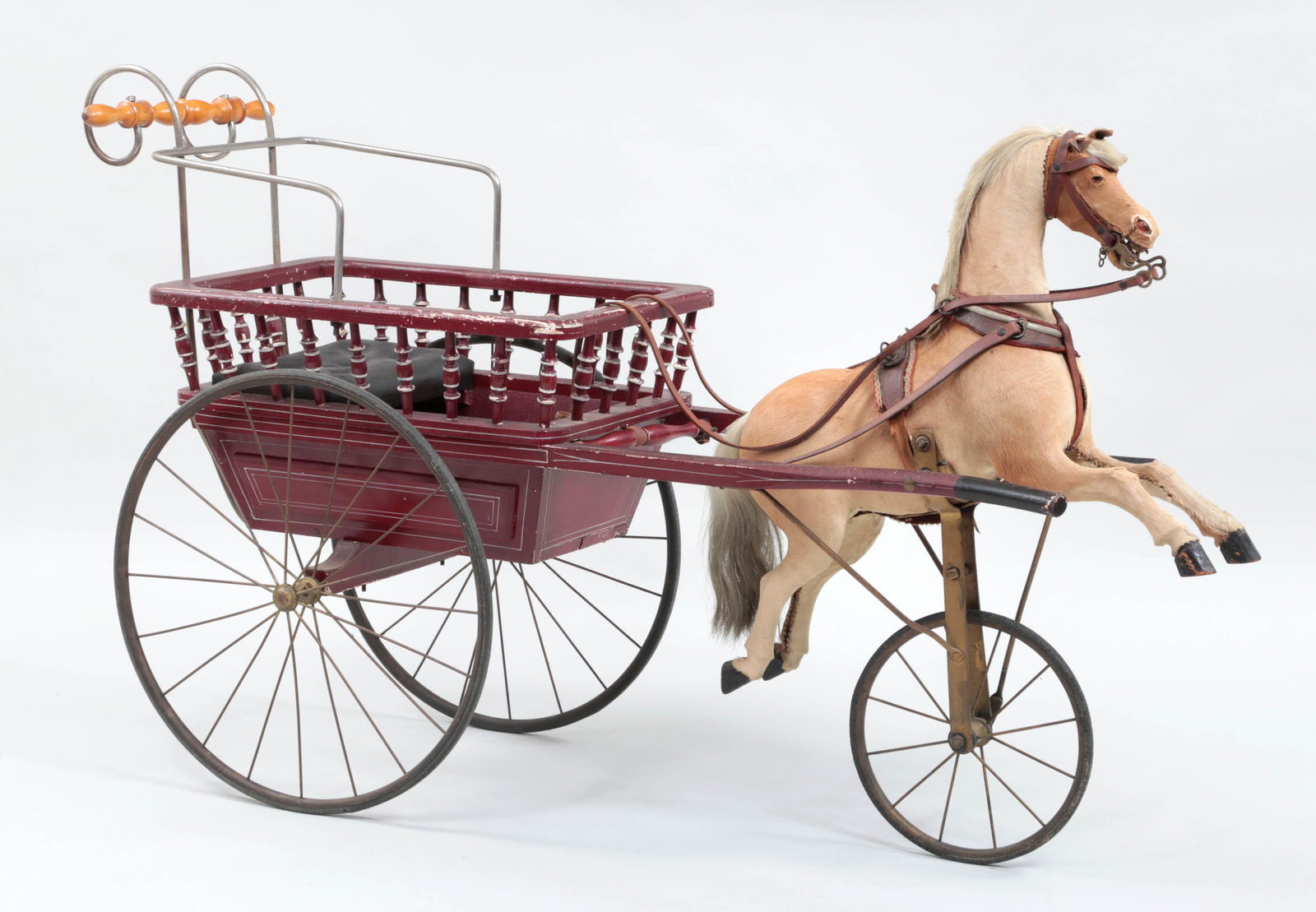 Child's wooden perambulator with galloping action: Child's wooden perambulator with galloping action animal hide covered horse, circa 1900. Splitting to animal hide and paint flaking. 34''h, 19''w, 60''l.