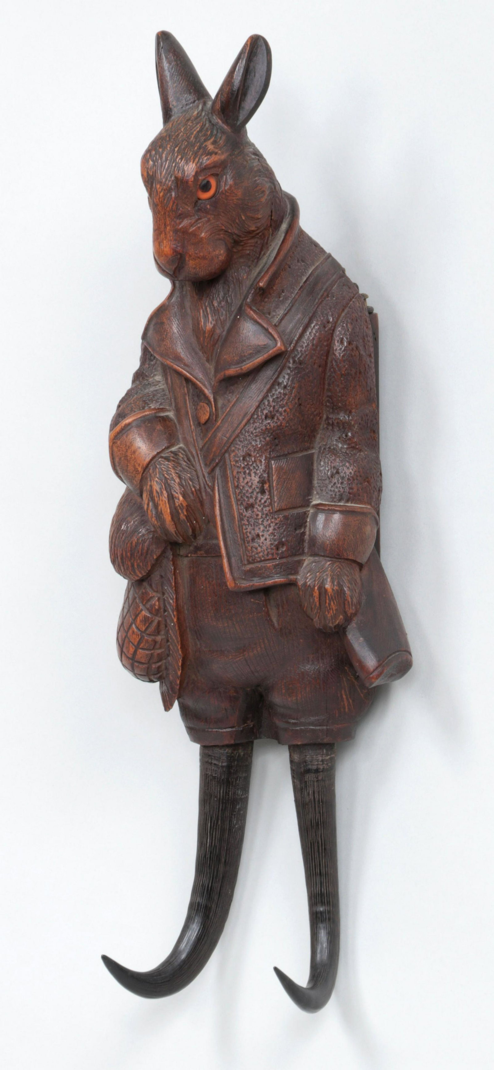 Black Forest rack with music box: Black Forest carved wood ''hunting hare'' wall-mounted coat/hat rack with music box, having glass eyes and antler hooks. Music box mechanism needs adjustment, repair to ears, gun, and backing, and min