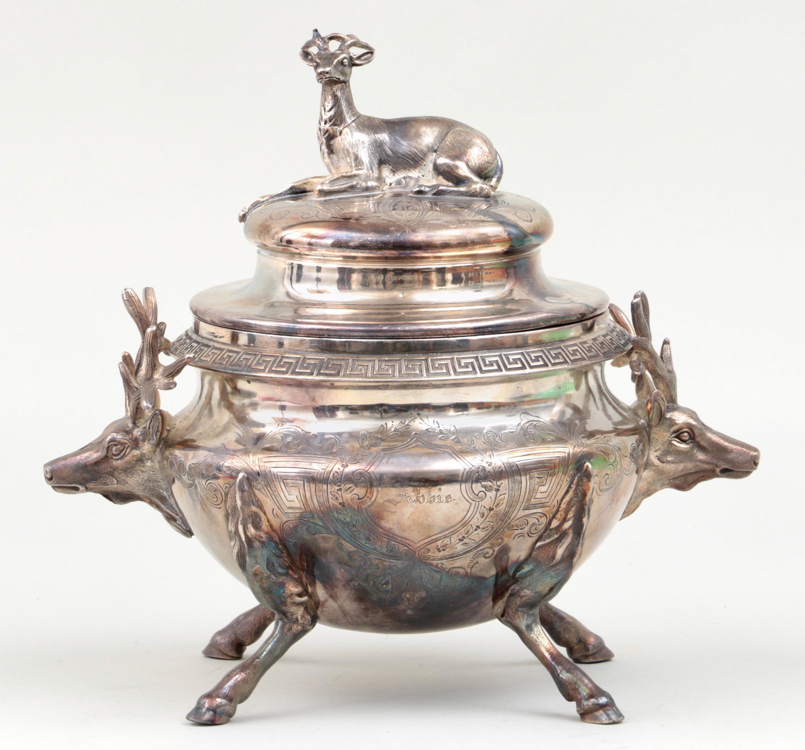 Covered stag motif silverplate serving dish: Covered stag motif silverplate serving dish with stag finial, applied stag handles, and engraved body on four hoof feet. Wear to plate. 11''h, 12-1/5''w, 9-3/4''d.