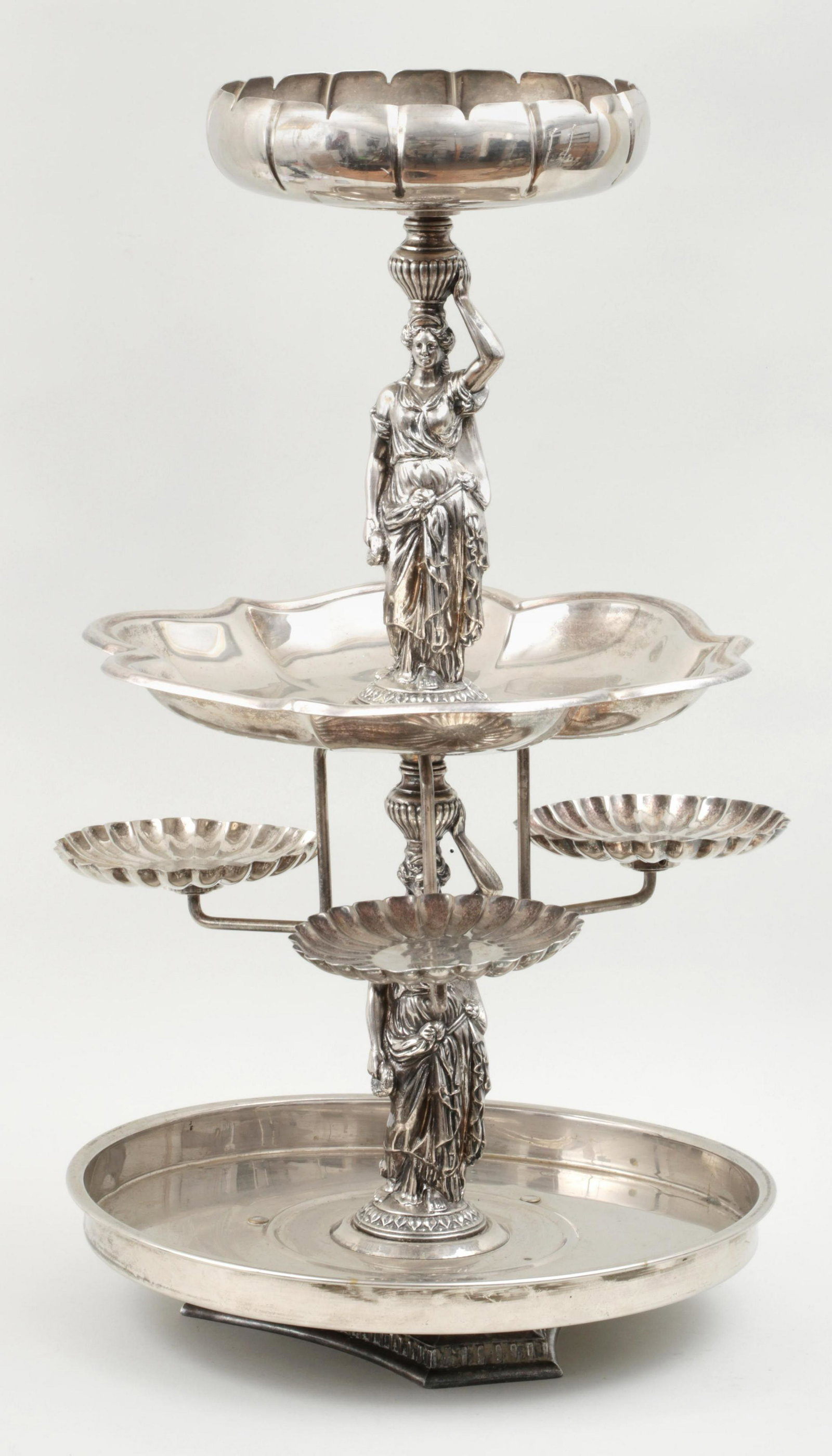 Large silverplate figural epergne: Large silverplate figural epergne with caryatid form supports between each tier and three small dropped dishes with scalloped rims. Minor wear to plate and dents to base. 29-1/2''h, 18''w, 17-1/2''d.