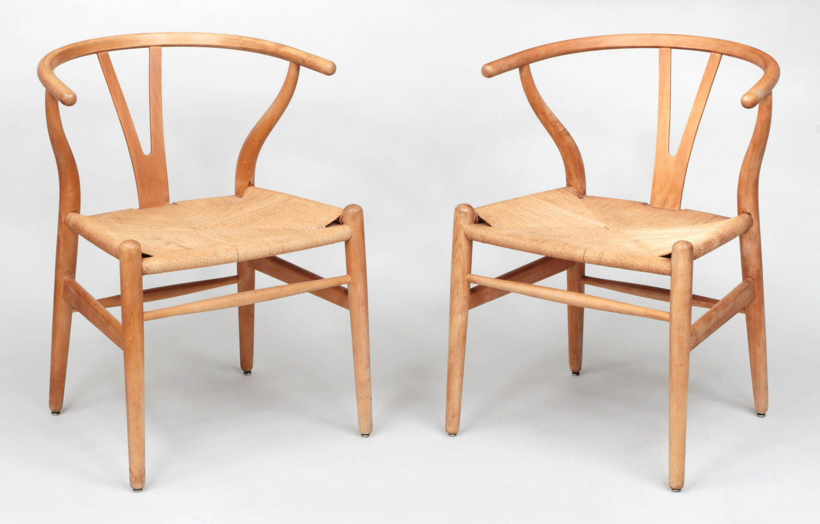 HANS J. WEGNER (Danish, 1914-2007): HANS J. WEGNER (Danish, 1914-2007), pair of wishbone chairs, silvered label to bottom. Some stains. 29''h, 22-1/2''w. 20-1/2''d.