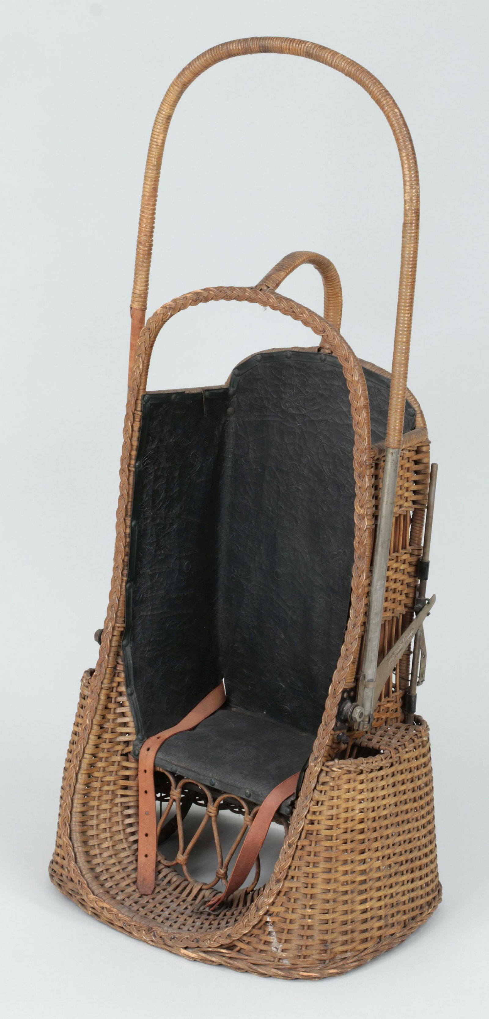 Luggage-style wicker folding baby carriage: Luggage-style wicker folding baby carriage, with embossed black leather seat and brown lap belt, rolls on two wheels, made by the Withrow Manufacturing Company of Cincinnati, Ohio, with a patent date