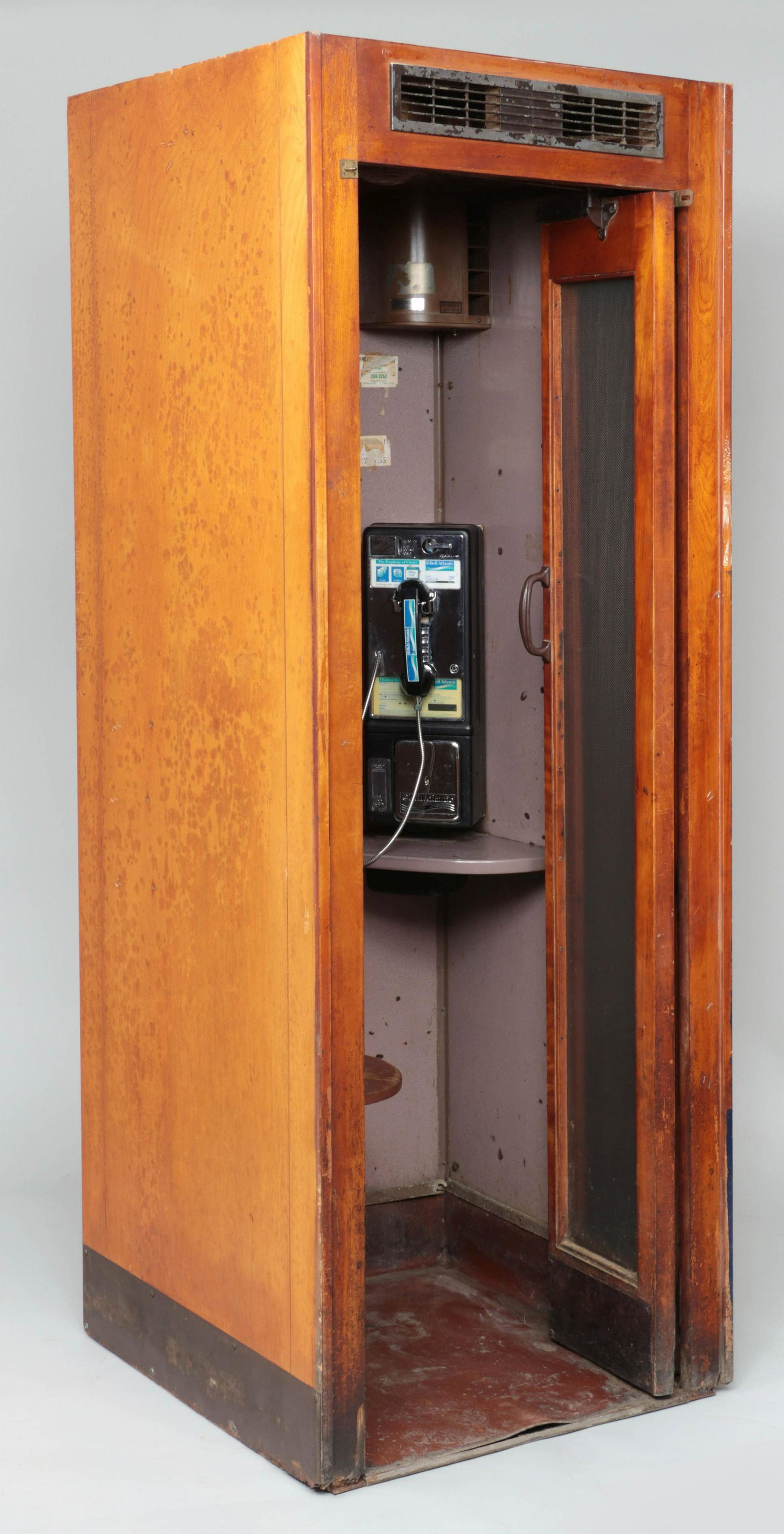 Wood telephone booth with phone: Wood telephone booth with phone, accordion doors, seat, light and ventilation fan. Wear from use, fan does not appear to be functioning. 83''h, 30-1/2''sq.