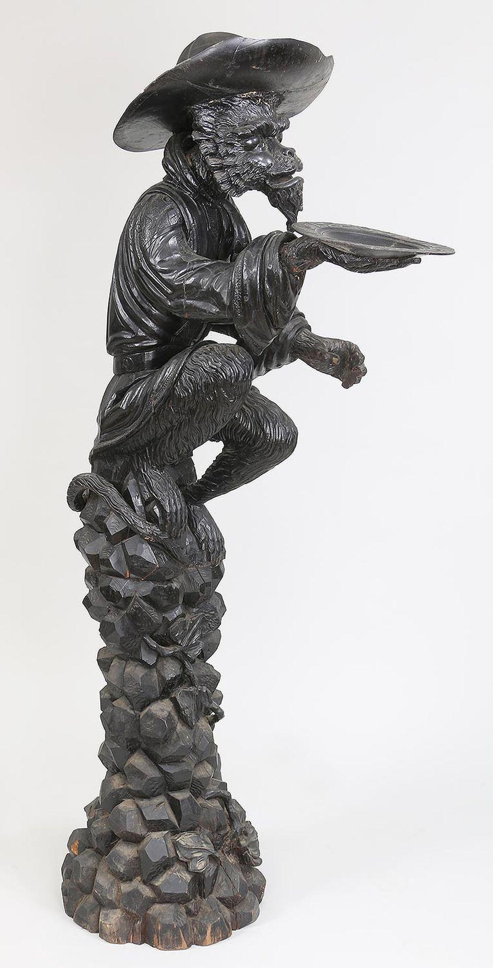 Large ebonized carved butler stand: Large ebonized carved butler stand as monkey seated on rocks with outstretched arm holding a plate, 19th/20th century. Loss to fingers, repairs, losses. 68-1/2''h.