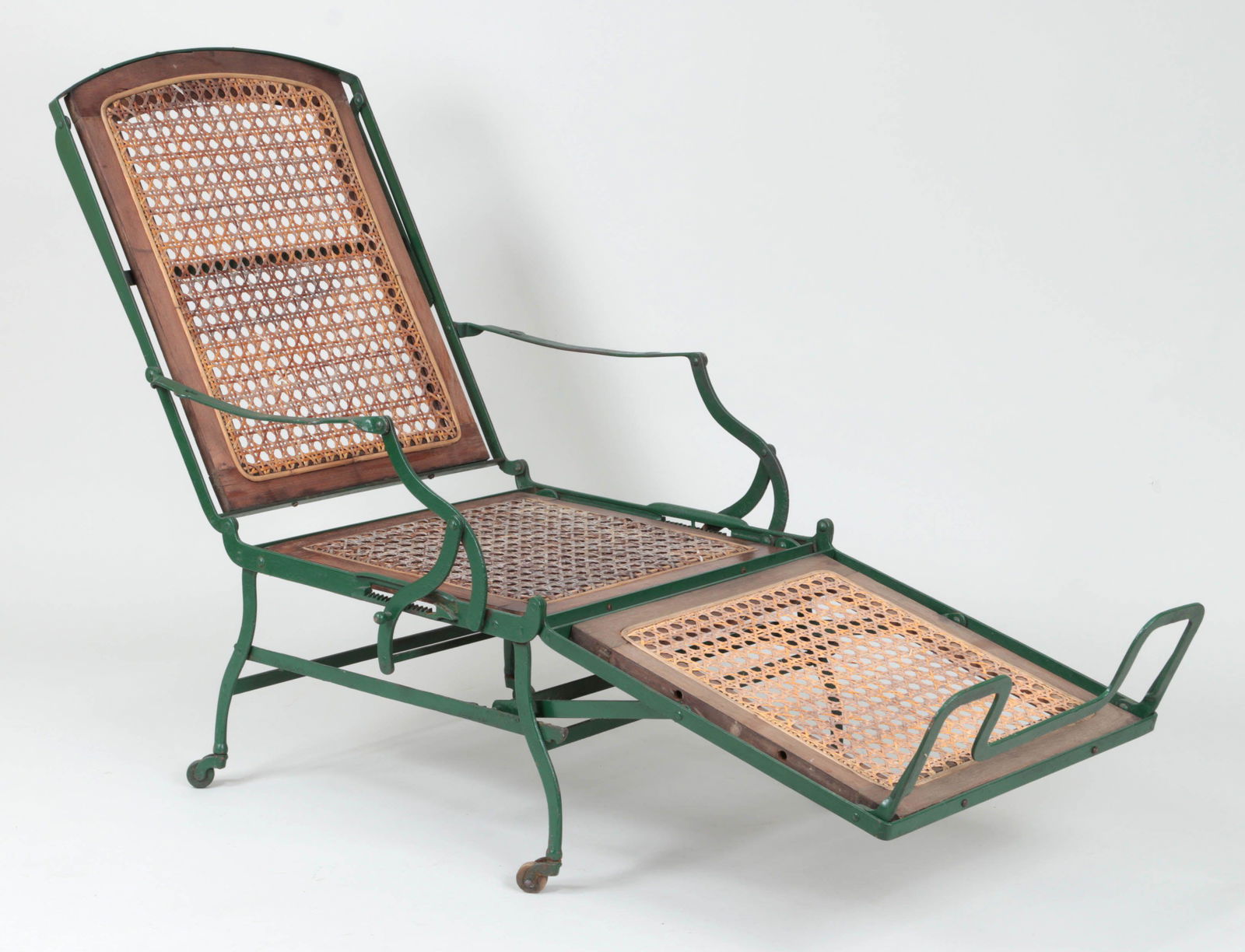 Wrought iron adjustable deck chair: Wrought iron adjustable deck chair with caned seat. Lacking wood armrest covers, some loss to caning. 42-1/2''h (upright), 26-1/4''w, 72-1/4''l (flat).