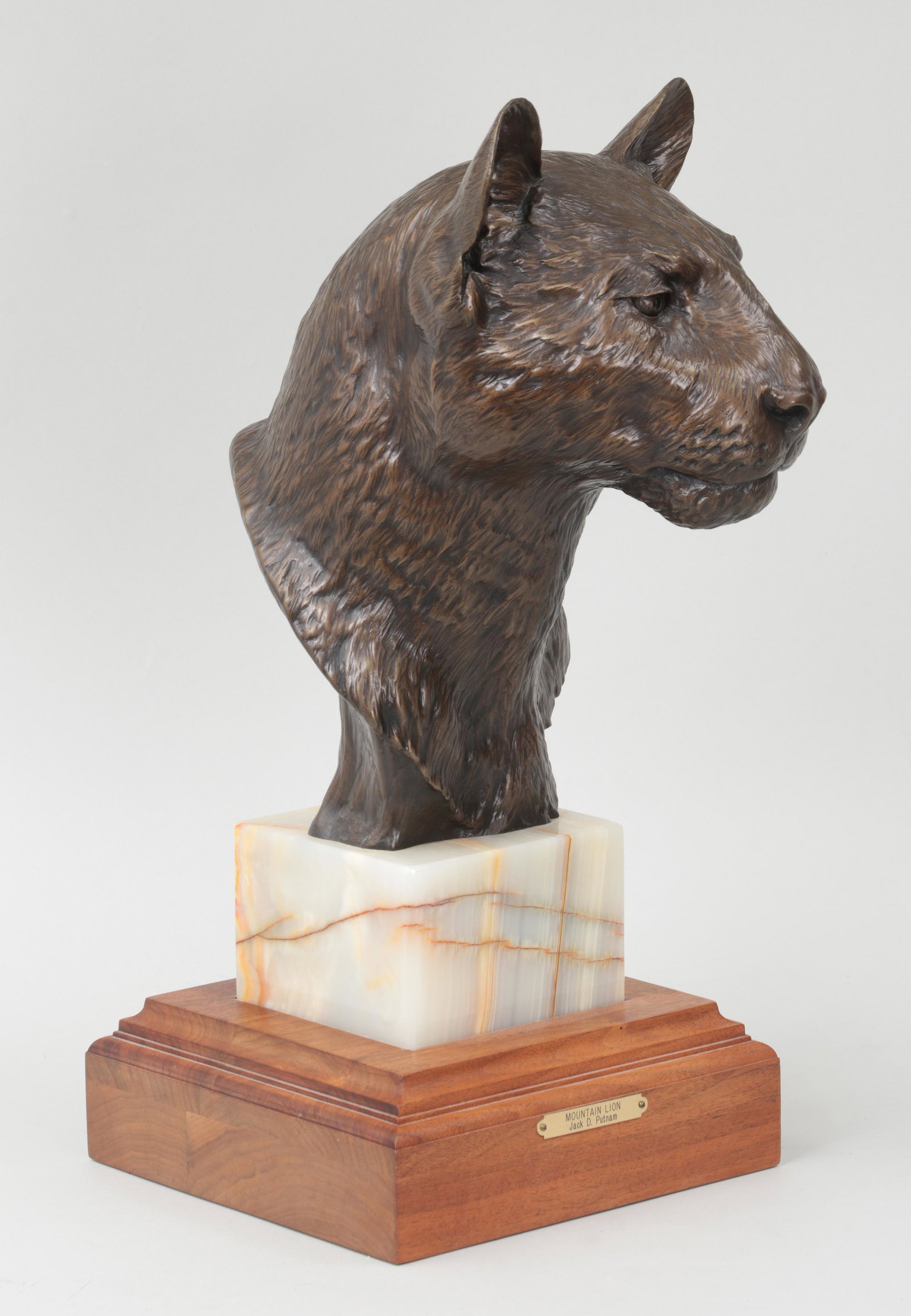 JACK D. PUTNAM: JACK D. PUTNAM (American, 1925-2009), ''Mountain Lion'', 1985, bronze with gold patina, signed, dated, and numbered 3/25. 23''h, 10-1/2''w, 13-1/2''d (including hardstone plinth and stepped walnut bas