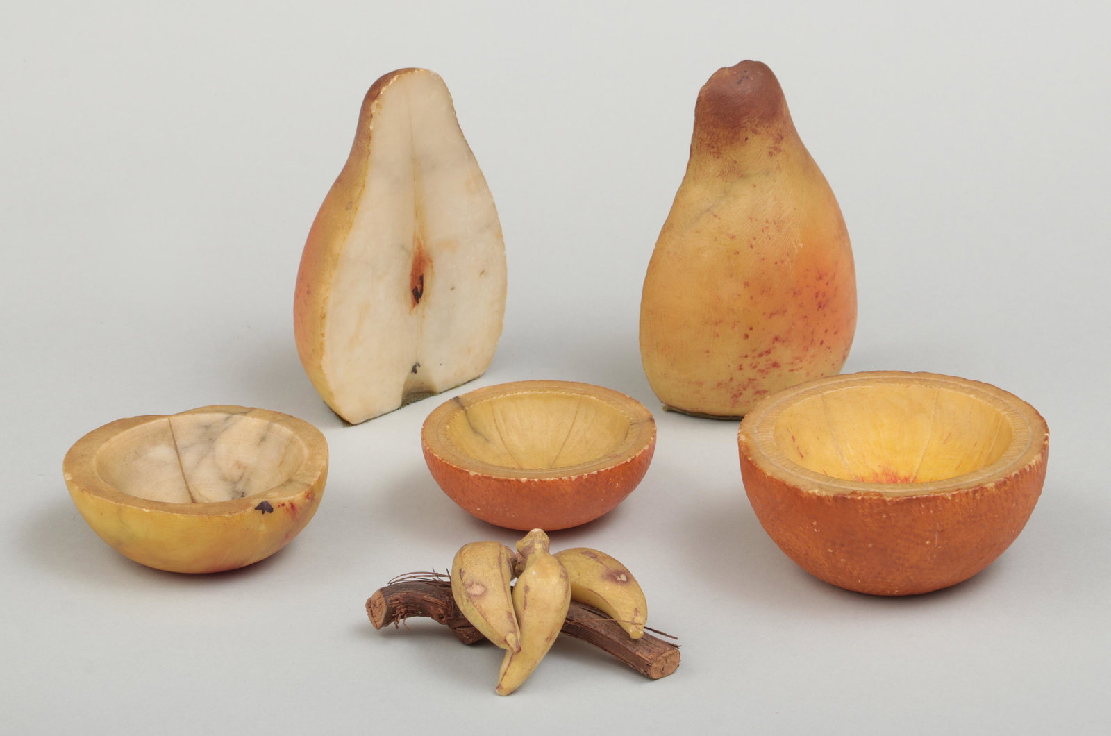 Group of (6) carved stone fruit: Group of (6) carved stone fruit, to include: set of sliced pear bookends; one small apple bowl; two small orange bowls; and small bunch of bananas. Bookends 5''h.