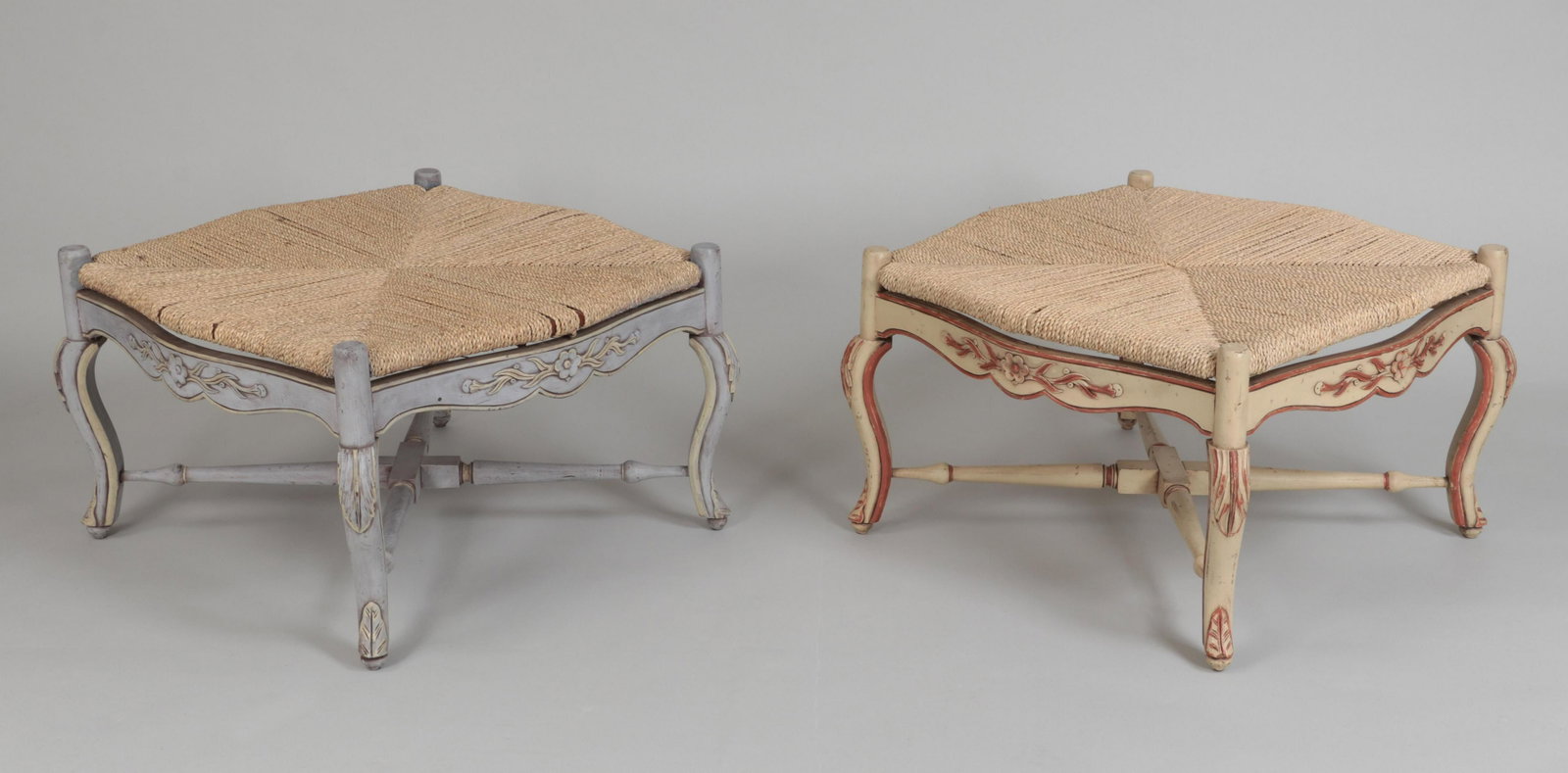 Pair of ottomans: Pair of carved and painted ottomans with woven rope seats, floral and foliate relief carved accents, raised on cabriole legs with x-form stretchers. Some wear. 15-1/2'', 26-1/2''sq.