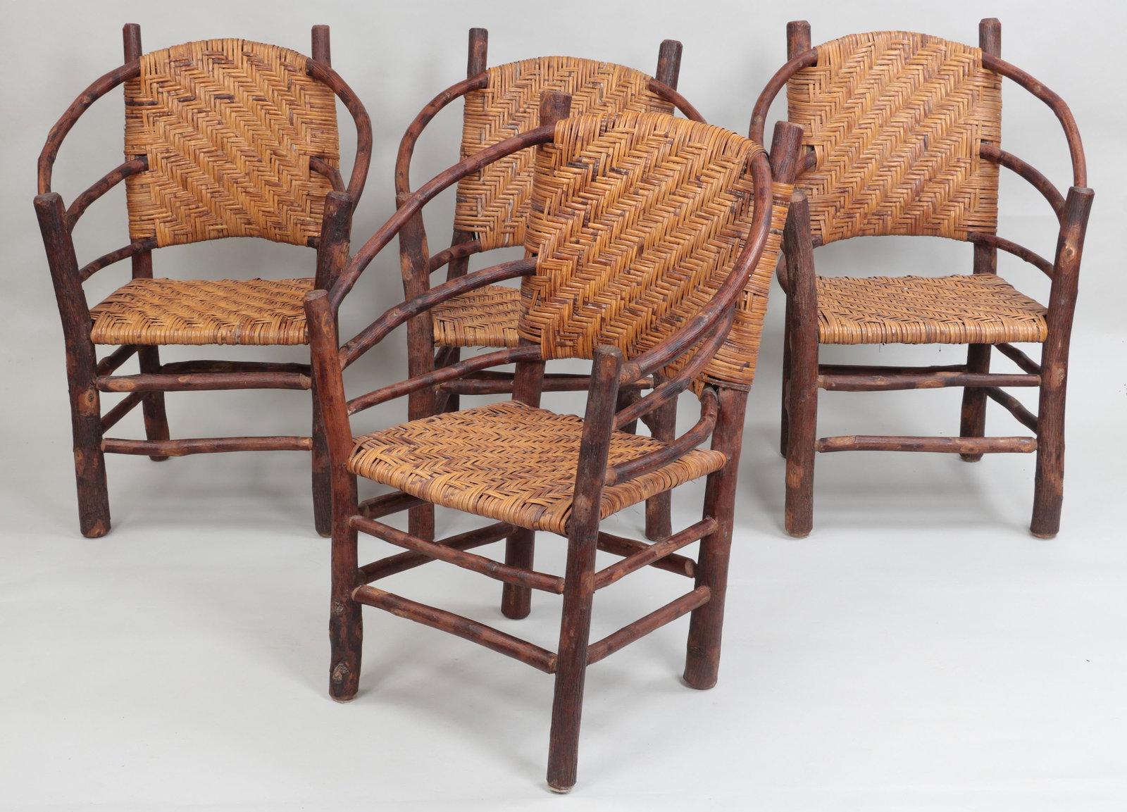 4 Old Hickory rustic armchairs: Set of (4) Old Hickory rustic armchairs with cane seats and backs. Wear from use, one armchair with split to one joint and one rear foot cut down. 35-1/2''h, 25-3/4''w, 22-1/2''d. Provenance: Acquired