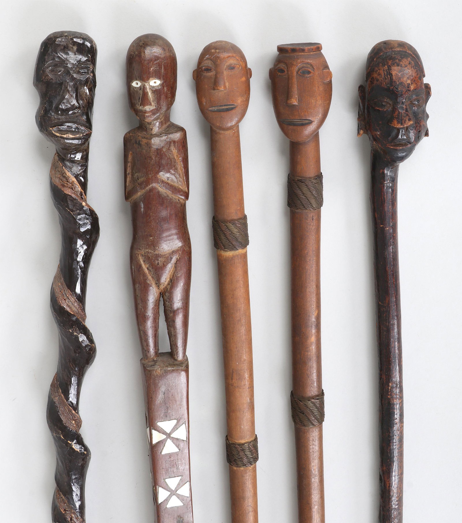 Folk Art carved walking sticks: Group of (5) Folk Art carved walking sticks, to include: (2) head canes with braided brass and copper wire bands, (one lacking ferrule); (2) hardwood head canes, (the shorter with splits, losses); and