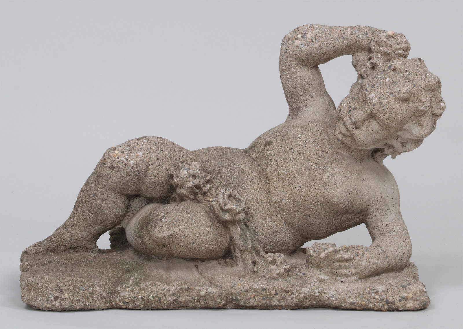Cast stone reclining putti: Cast stone reclining putti with draped rose garland. Weathered. 15-3/4''h, 24-1/4''w, 10-1/4''d.