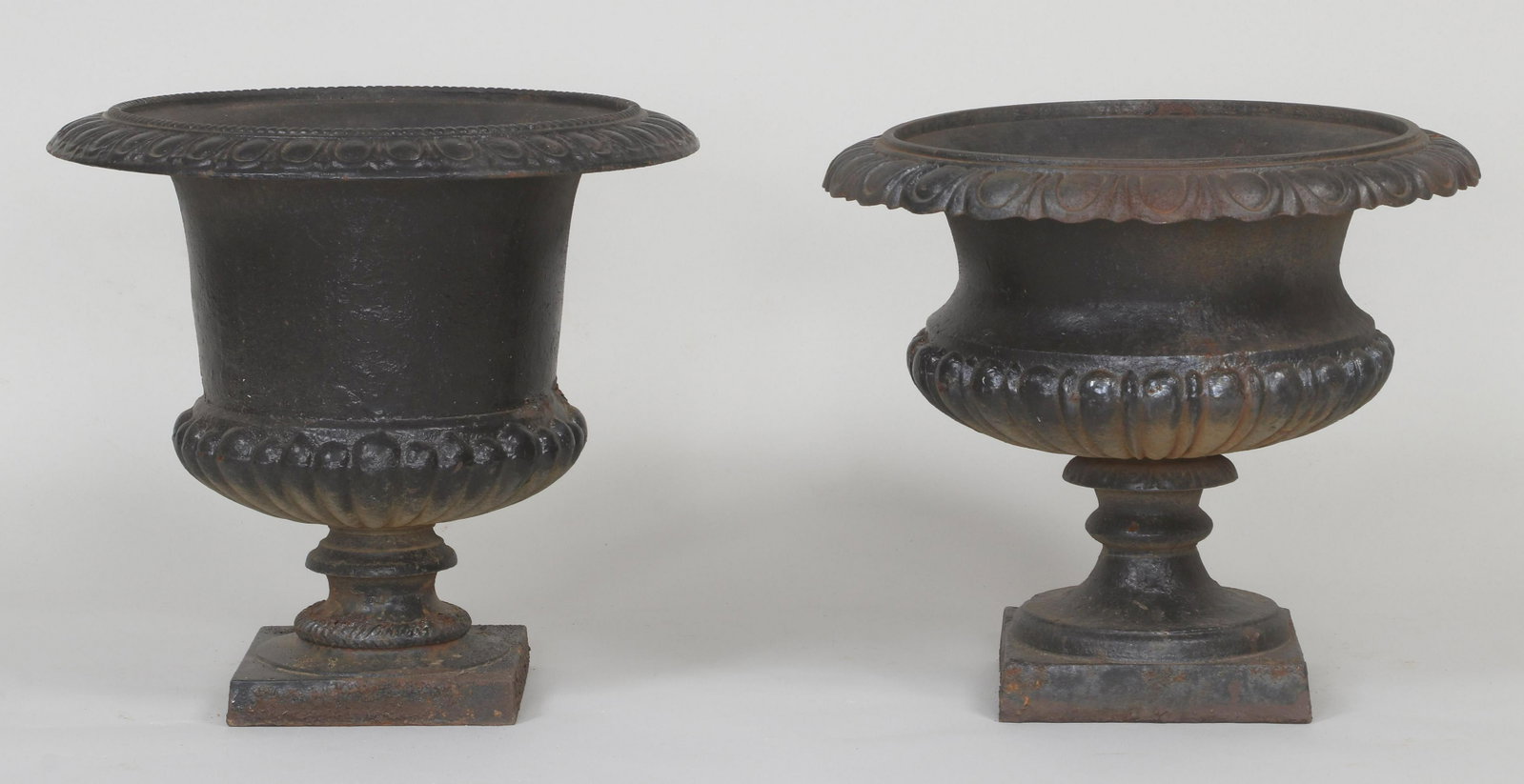 Assembled pair of cast iron campana urns: Assembled pair of neoclassical style cast iron campana urns, both semi-lobed with egg-and-dart rim, black-painted. Rust. Larger 17-1/2''h, 19''dia.