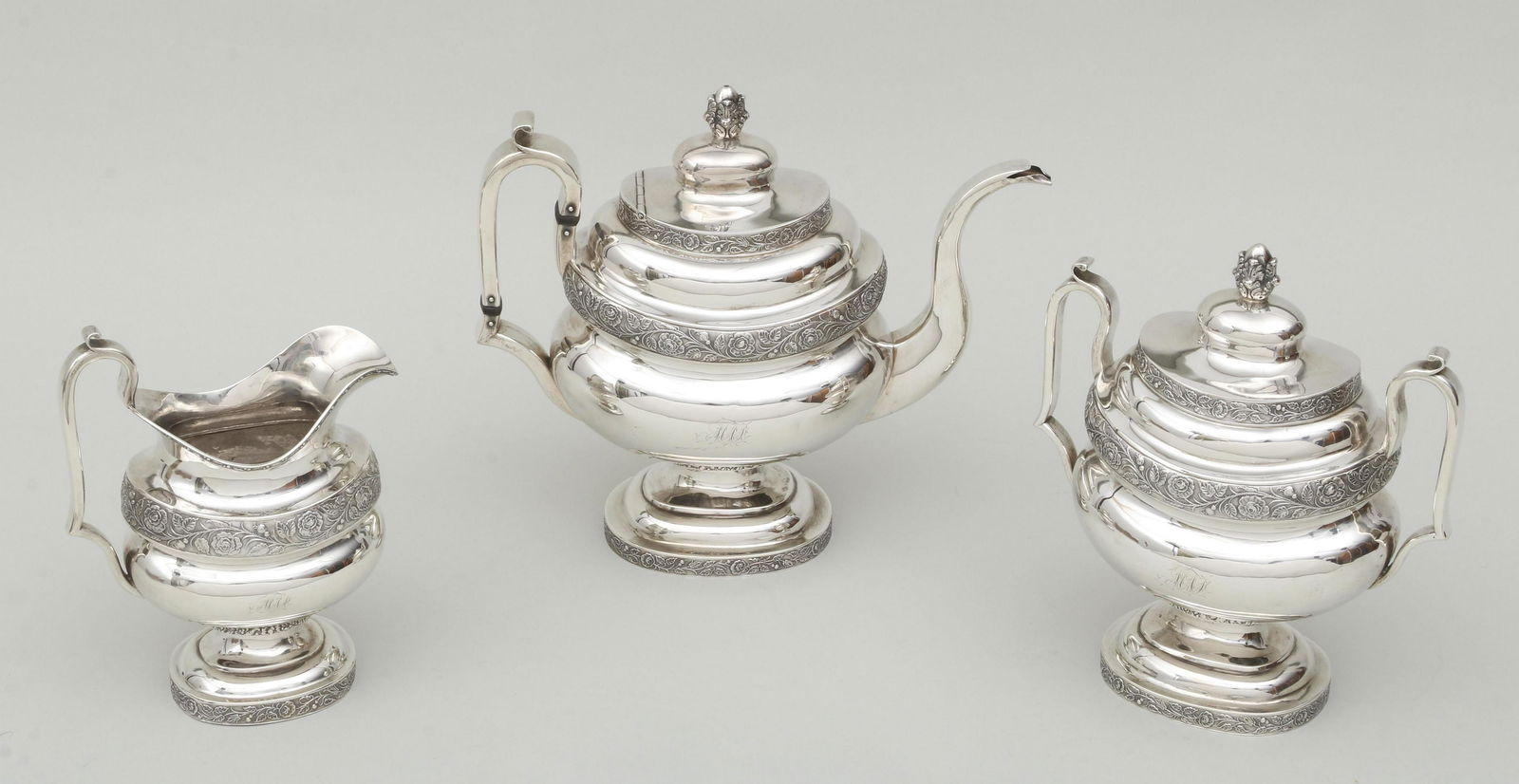 Garrett Eoff, 19th century, New York: American three-piece coin silver tea set, Garrett Eoff, New York, early 19th century, having floral die-rolled decoration, to include: teapot; creamer; and two-handled lidded sugar, each with engraved