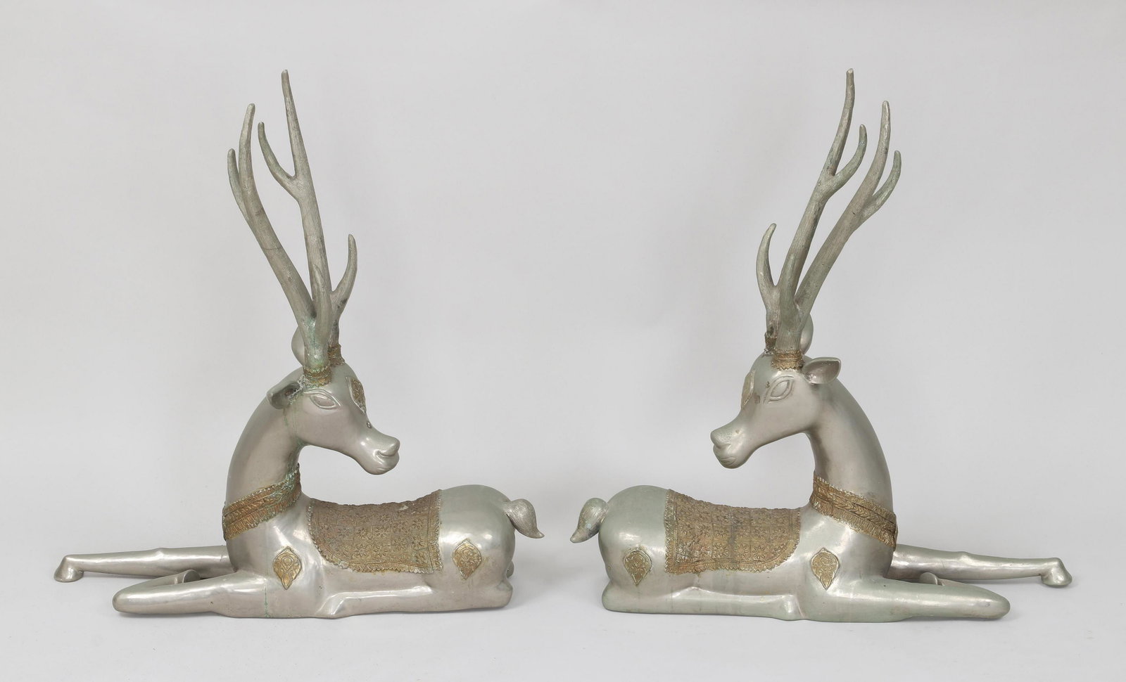 Pair of silvered brass recumbent stags: Pair of silvered brass recumbent stags, 20th century, having bronze saddles with Moorish-style decoration. Some areas of corrosion. 32''h, 30-1/2''l, 9''w.