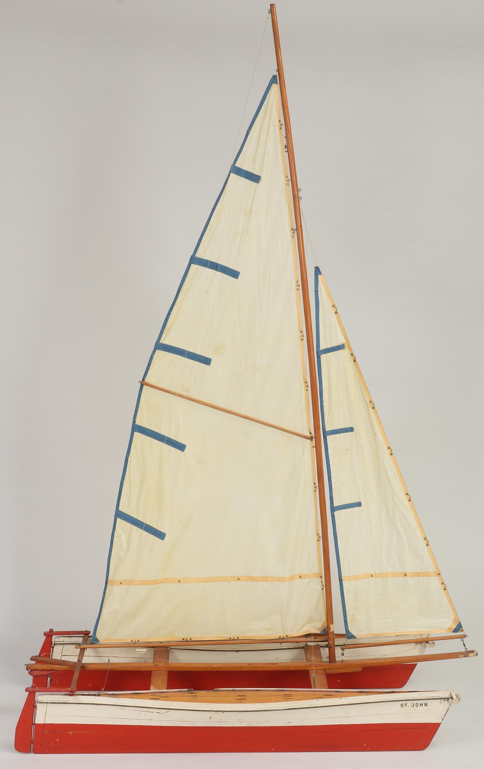Wood catamaran pond sailer: Wood catamaran pond sailer with red hull and varnished deck, named ''St. John''. Small losses and wear from use. 70-1/2''h, 45-3/4''w, 18''d.