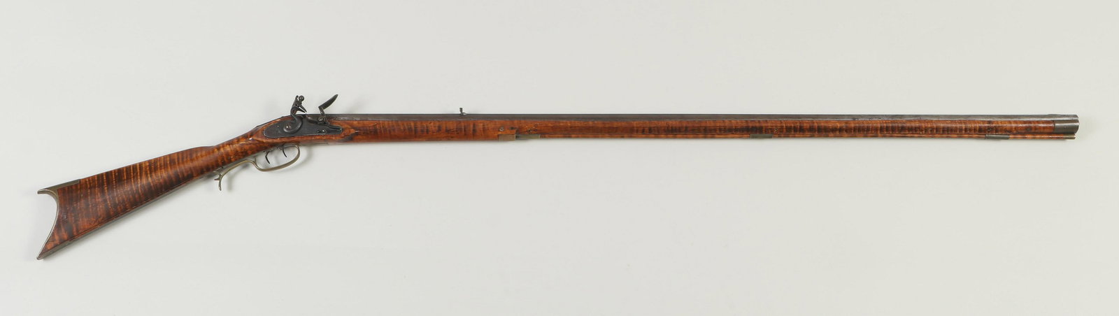 Kentucky flintlock rifle by Henry Parker: Kentucky flintlock rifle by Henry Parker. The octagon barrel measures 45-3/4'' with a notched rear sight and blade front. The full-length tiger maple stock with cheek piece may have had the tiger grai