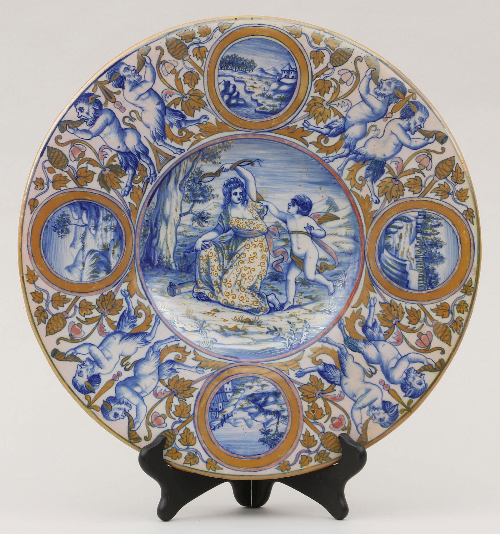 Italian majolica charger: Italian majolica charger in the style of Giorgio Andreoli, depicting Venus disarming Cupid, gilt detailing and border having horn-playing satyrs and cartouches with countryside landscapes, titled ''An