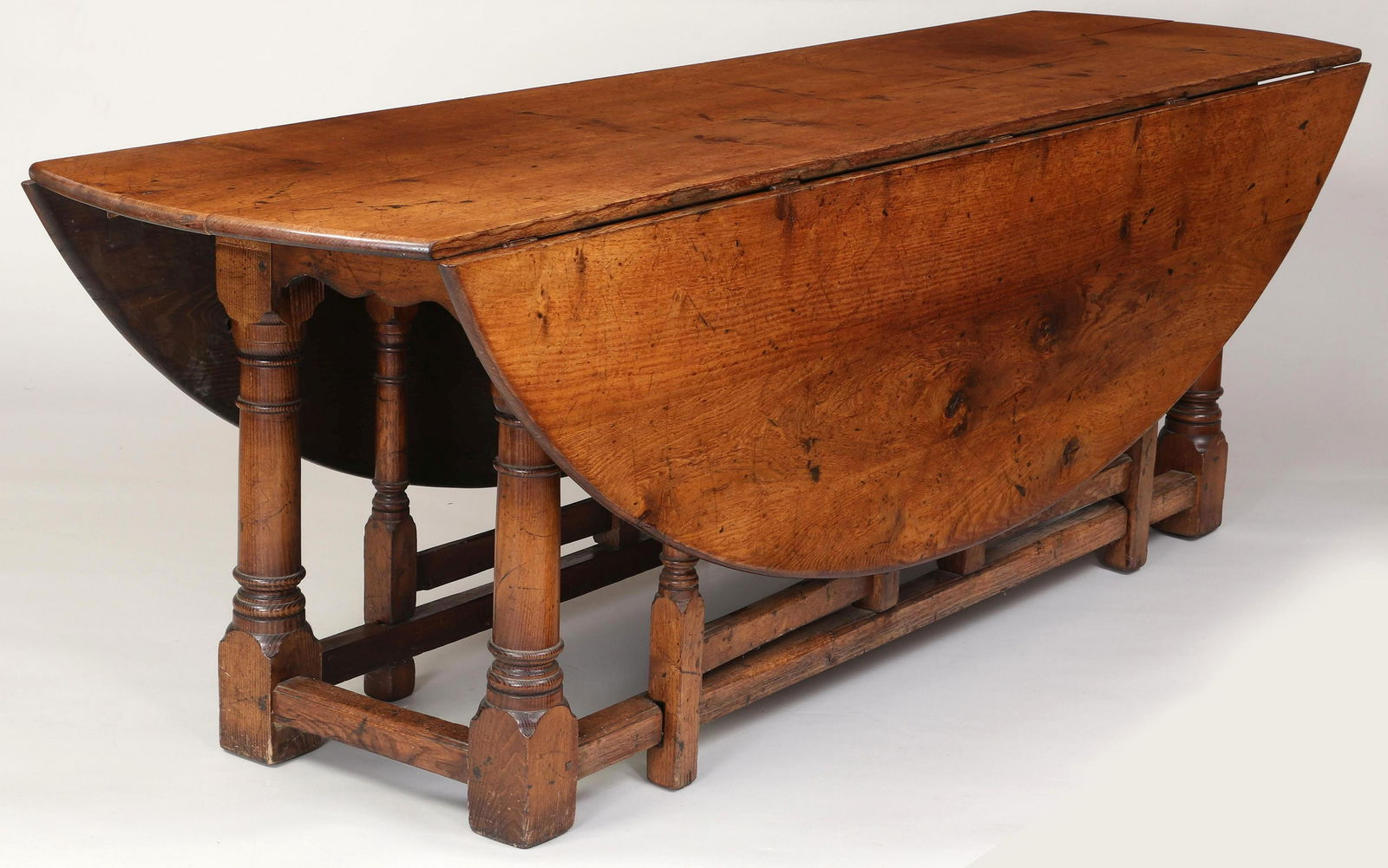 Large English oak gateleg dining table: Large English oak gateleg dining table, with oval drop leaf top, double swing out turned legs. Sunbleaching to top and one leaf. 29''h, 90''w, 65-1/2''d(open), 24-3/4''d(closed).