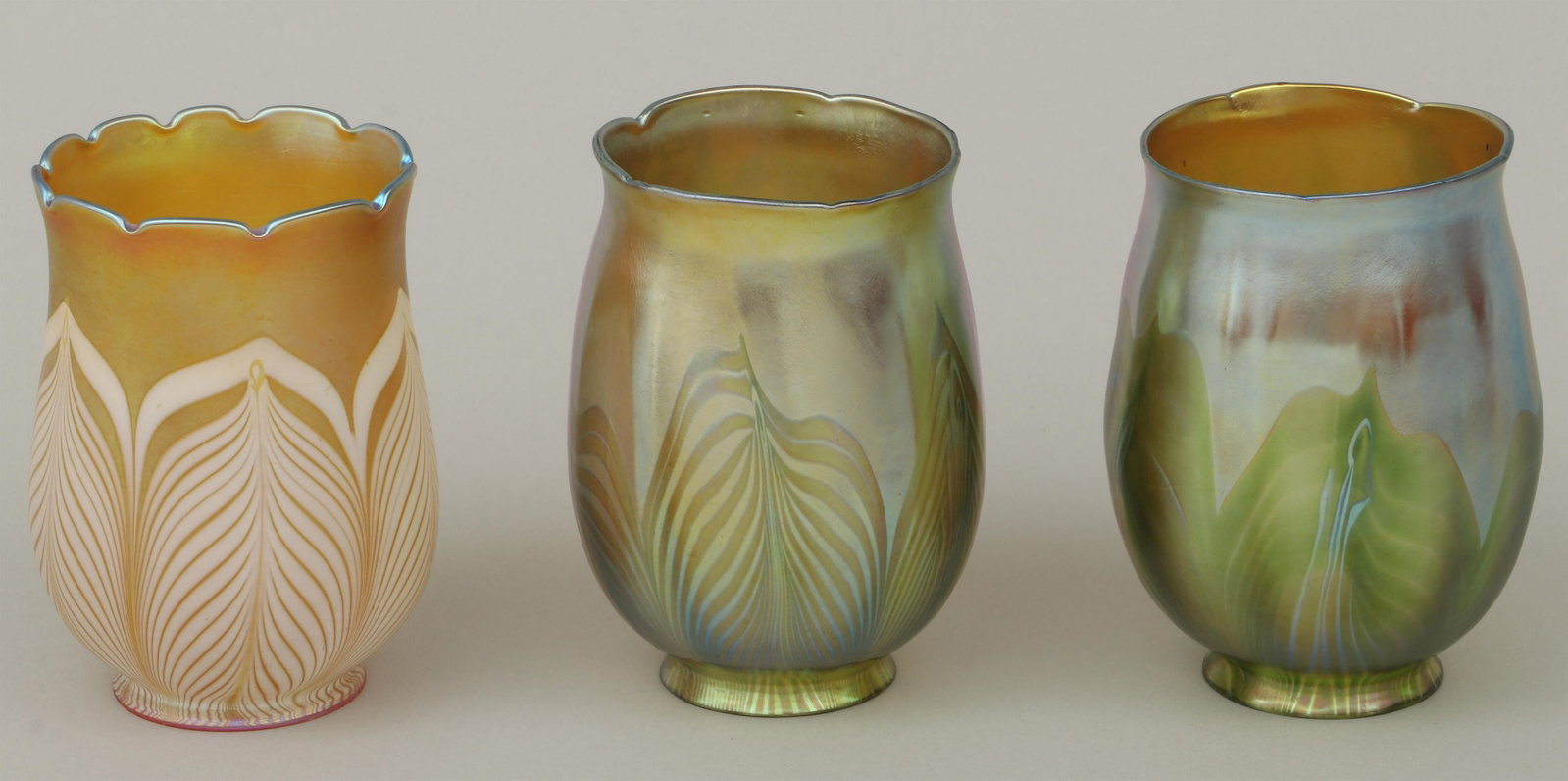Group of (3) iridescent glass shades: Group of (3) iridescent glass shades, to include: pair of Tiffany Studios Favrile glass floriform shades, with green pulled feather design, signed ''L.C.T'' to inside of rims, one numbered ''687'' to 