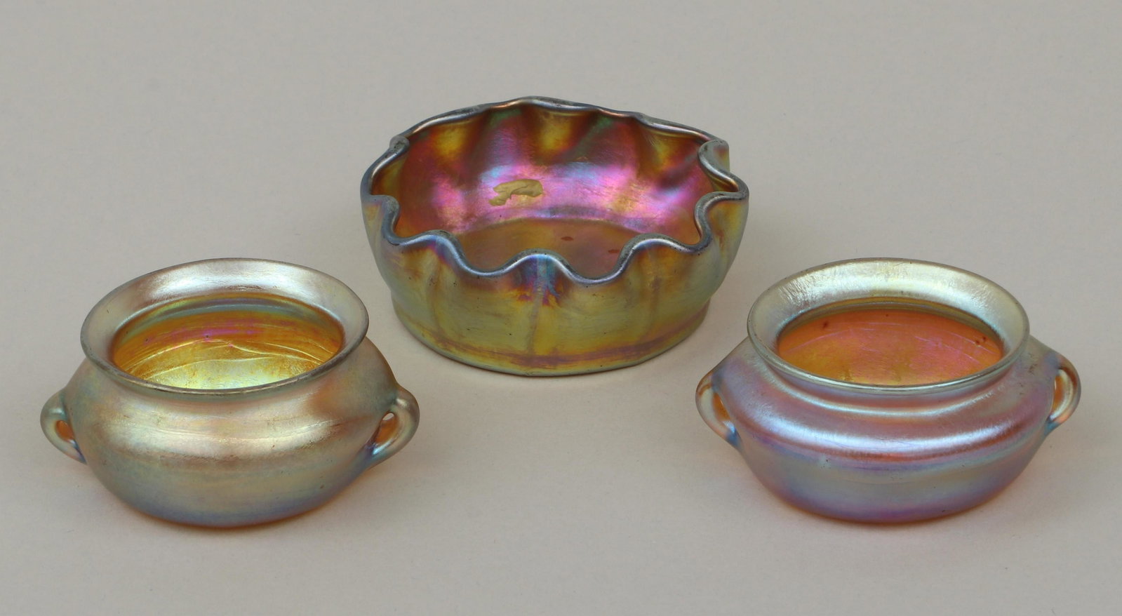Group of (3) miniature Tiffany Studios: Group of (3) miniature Tiffany Studios Favrile glass vessels, to include: (2) miniature vases, with flared rims and handles, signed ''L.C.T.'' and incised ''620'' to bottoms, (minor wear); and bowl wi