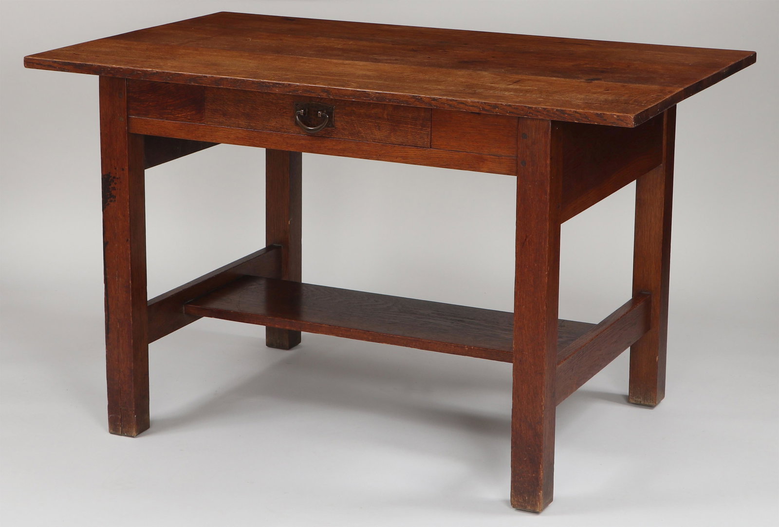 GUSTAV STICKLEY library table, #653: GUSTAV STICKLEY (American, 1858-1942), single drawer library table, #653, with stretcher shelf, paper label and red decal inside drawer. Shows wear and staining from use, appears to be repinned. 29-1/