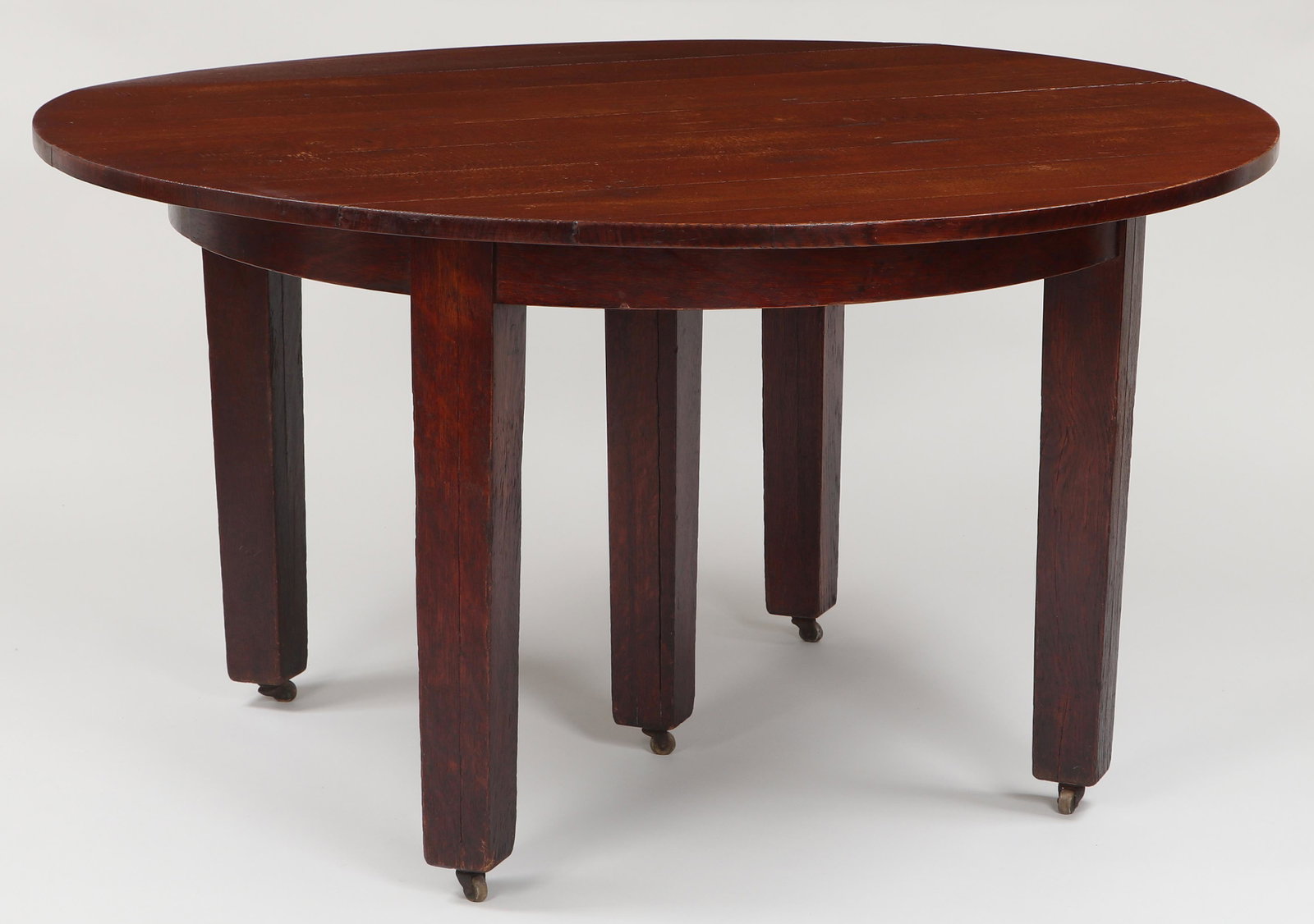 GUSTAV STICKLEY (American, 1858-1942): GUSTAV STICKLEY (American, 1858-1942) dining table, #633, circular top supported by five square tapering legs on casters, paper label to bottom, with (6) original 11'' leaves in crate. Shows heavy wea