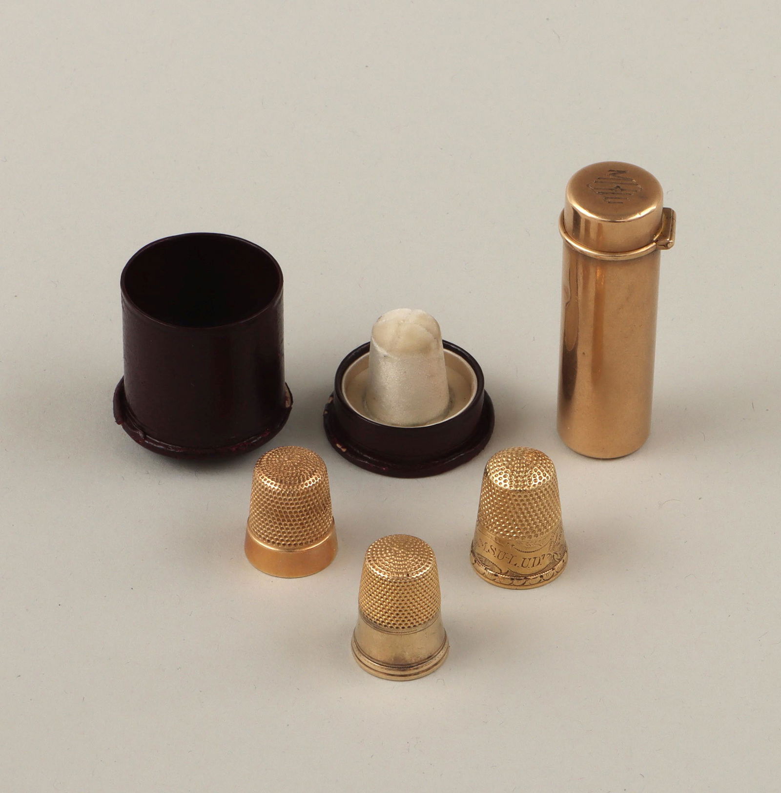 14k gold sewing items: Group of (4) 14k gold sewing items, to include: needle case, with hinged lid, monogrammed on top, stamped with ''14K'' and an ''acorn'' maker's mark inside lid, (minor dents); and (3) thimbles, compri