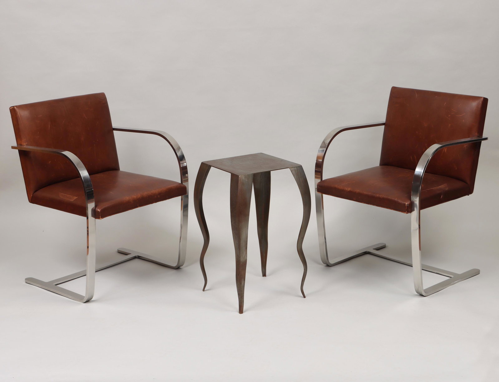 Knoll International ''BRNO'' armchairs: Pair of MIES VAN DER ROHE for Knoll International ''BRNO'' chrome armchairs with leather upholstery, one chair with 1977 label; along with a steel table side table. Leather with scuffs and stains, tab