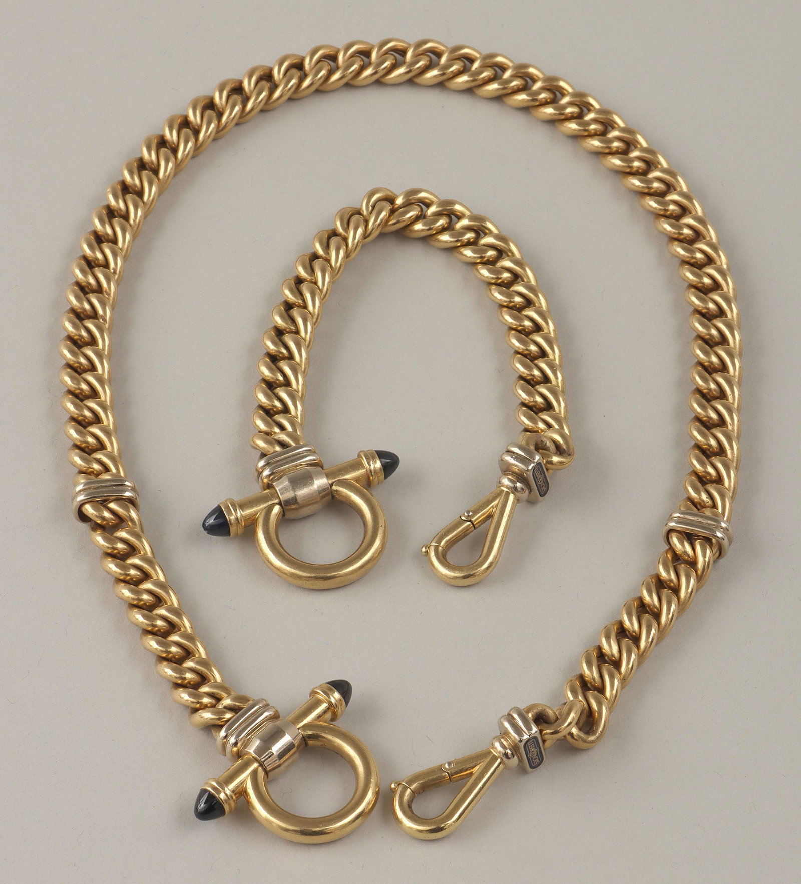 Signoretti 18k gold jewelry: Two-piece set of Signoretti 18k gold jewelry, each having gold curb chain and clasp decorated with (2) blue stones, to include: necklace; and bracelet. Bracelet with nick to one stone. Marked on clasp
