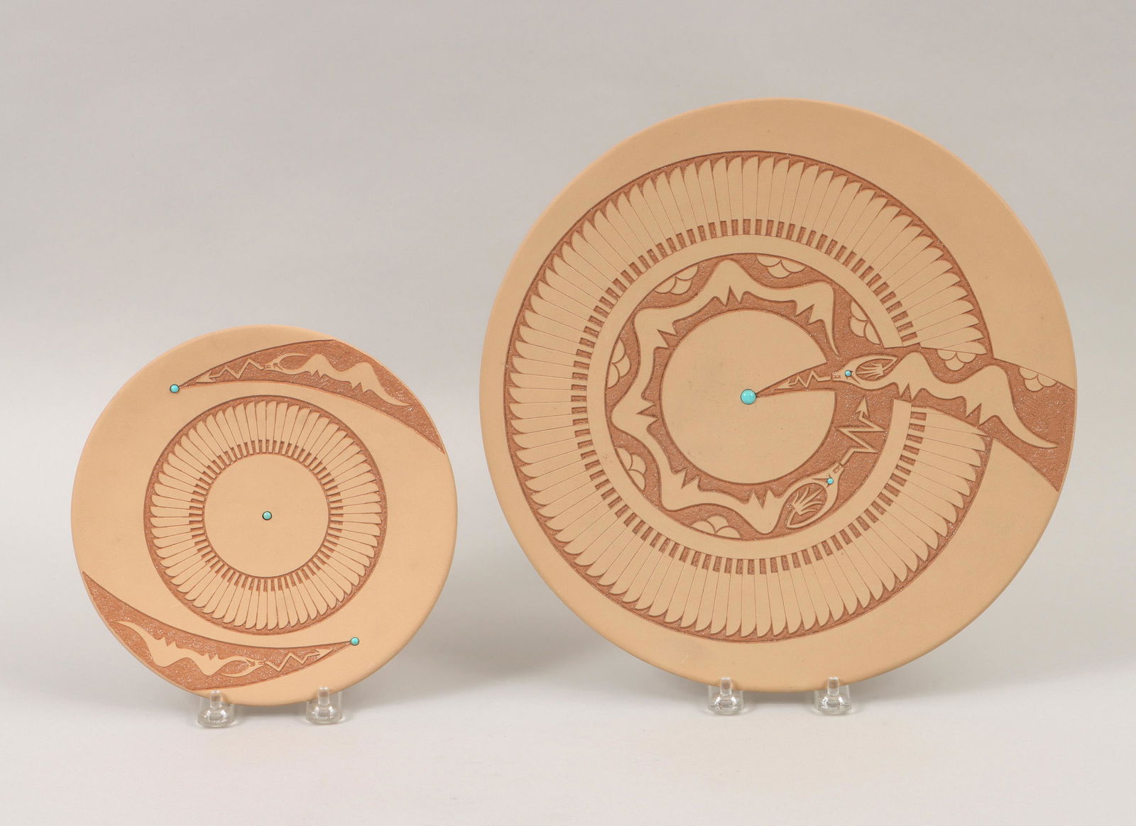 JOHN GONZALES: JOHN GONZALES (San Ildefonso Pueblo, b. 1955), group of (2) sgraffito-carved buffware plates, each having incised areas with micaceous clay slip, turquoise cabochons, feathers and two Avanyu, 1998, to