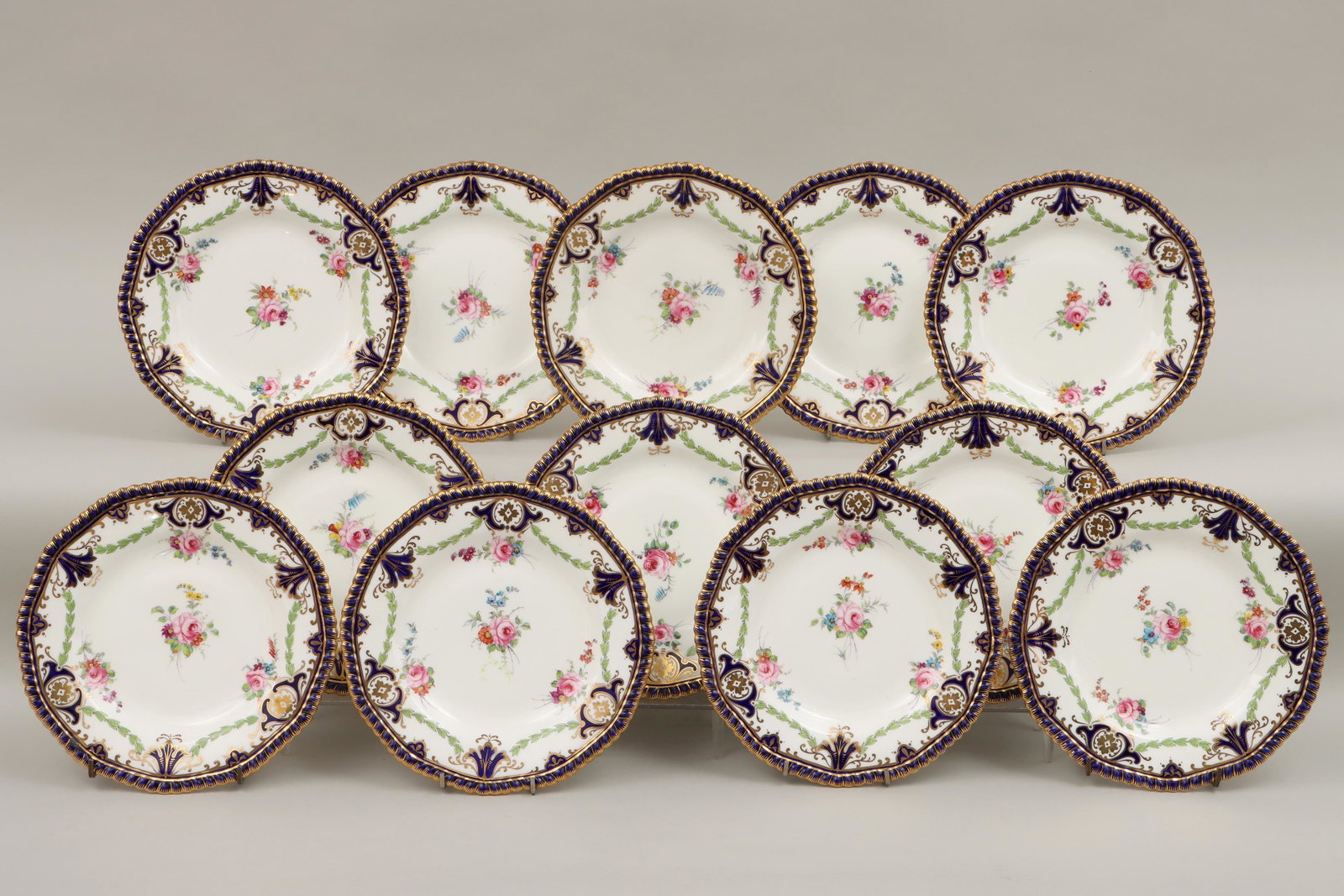 Set of (12) Wedgwood: Set of (12) Wedgwood hand-painted porcelain plates, having floral and foliate design and scalloped cobalt edges with gilt details, marked and numbered to bottom, some with indecipherable impressed mar