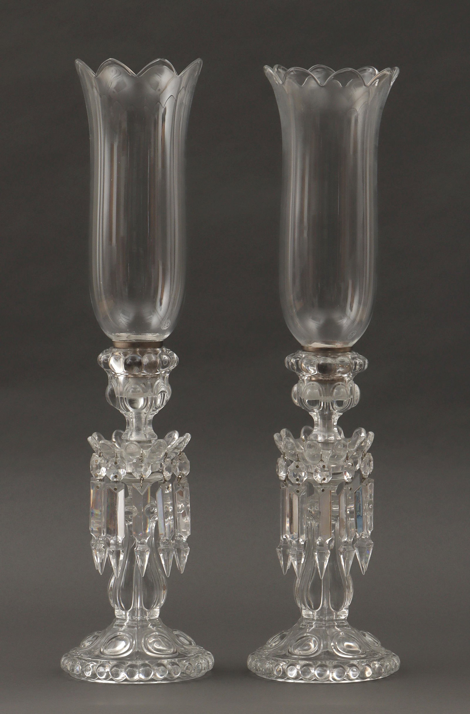 Pair of Baccarat crystal hurricane lamps: Pair of Baccarat crystal hurricane lamps, having molded bases with hanging prisms, shades and bases with Baccarat marks. One base with minor scratches and fleabites; some prisms with minor losses at t