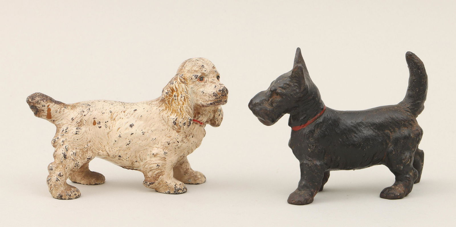 Cast iron dog doorstops: Group of (2) solid cast iron dog doorstops, painted, to include: Scottish terrier; and spaniel. Some paint loss, oxidation, accretion. Larger (Scottie) 5''h, 6-1/2''w, 2-1/2''d. IMPORTANT SHIPPING INF