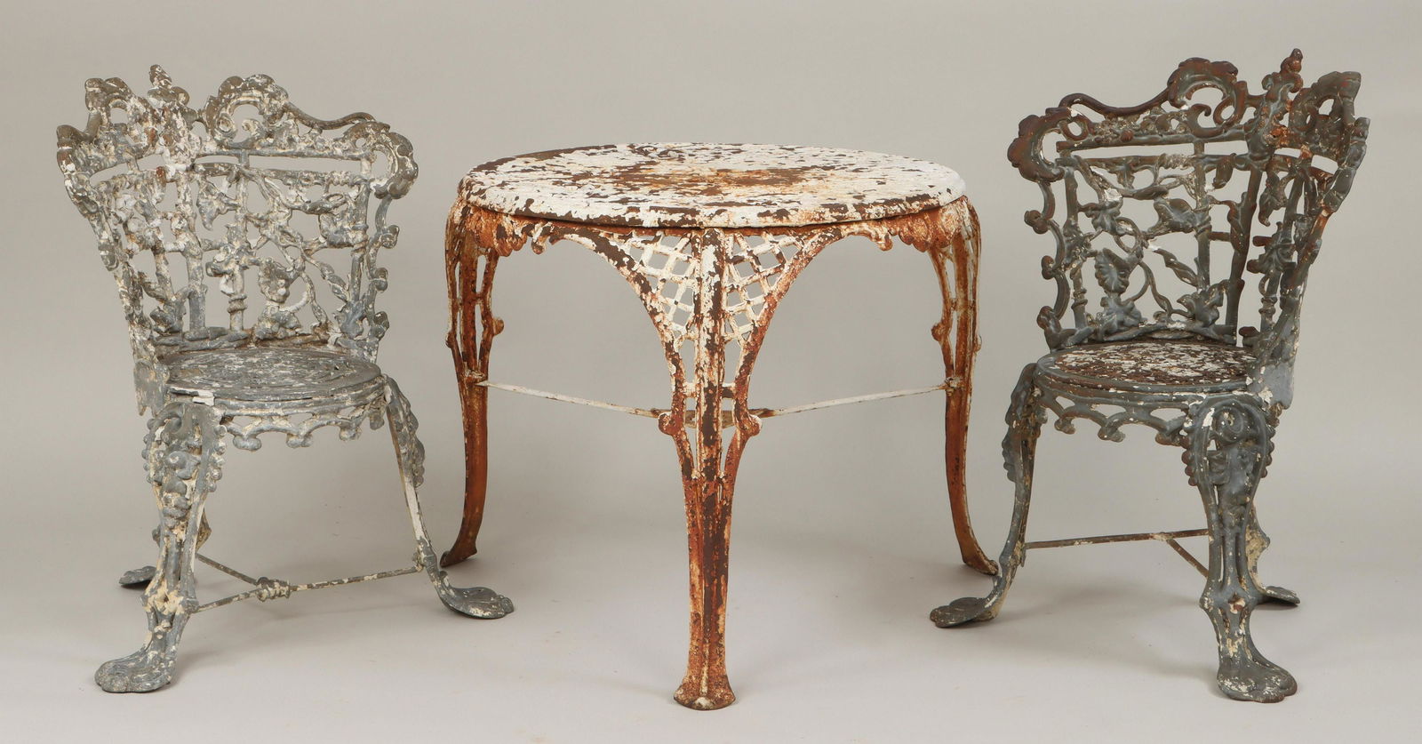 Cast iron three-piece set, 19C: Cast iron three-piece garden set, to include: pair of 19th century chairs in the ''Morning Glory'' pattern, with circular seats, (seats are different patterns); and early 20th century circular table w