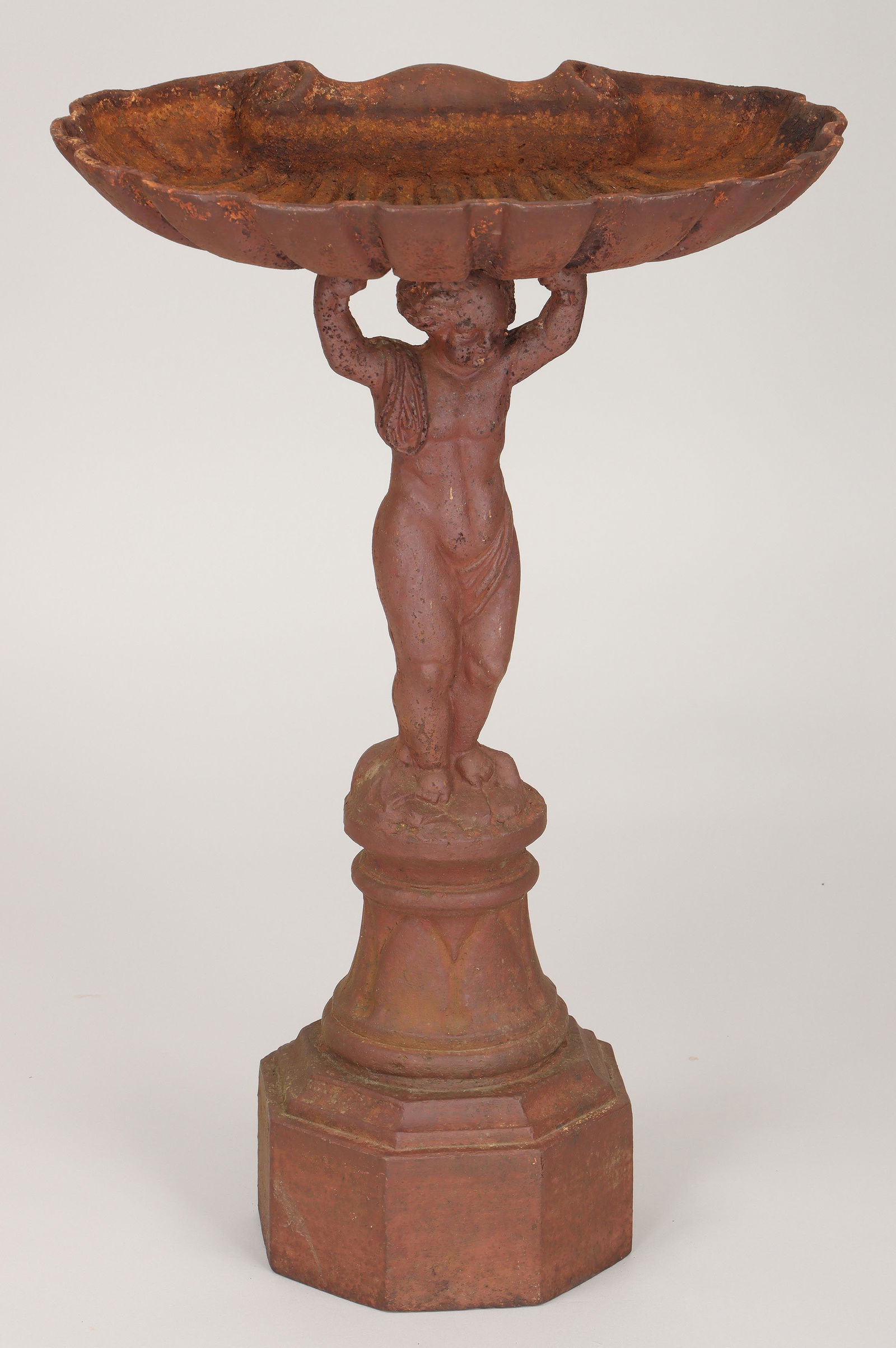 Cast iron figural birdbath: Cast iron figural birdbath with shell basin and standing putto support. Surface rust. 32-3/4''h. IMPORTANT SHIPPING INFORMATION 1 - LIVE-SHIPPING : The service is provided by Liveauctioneers. This opt