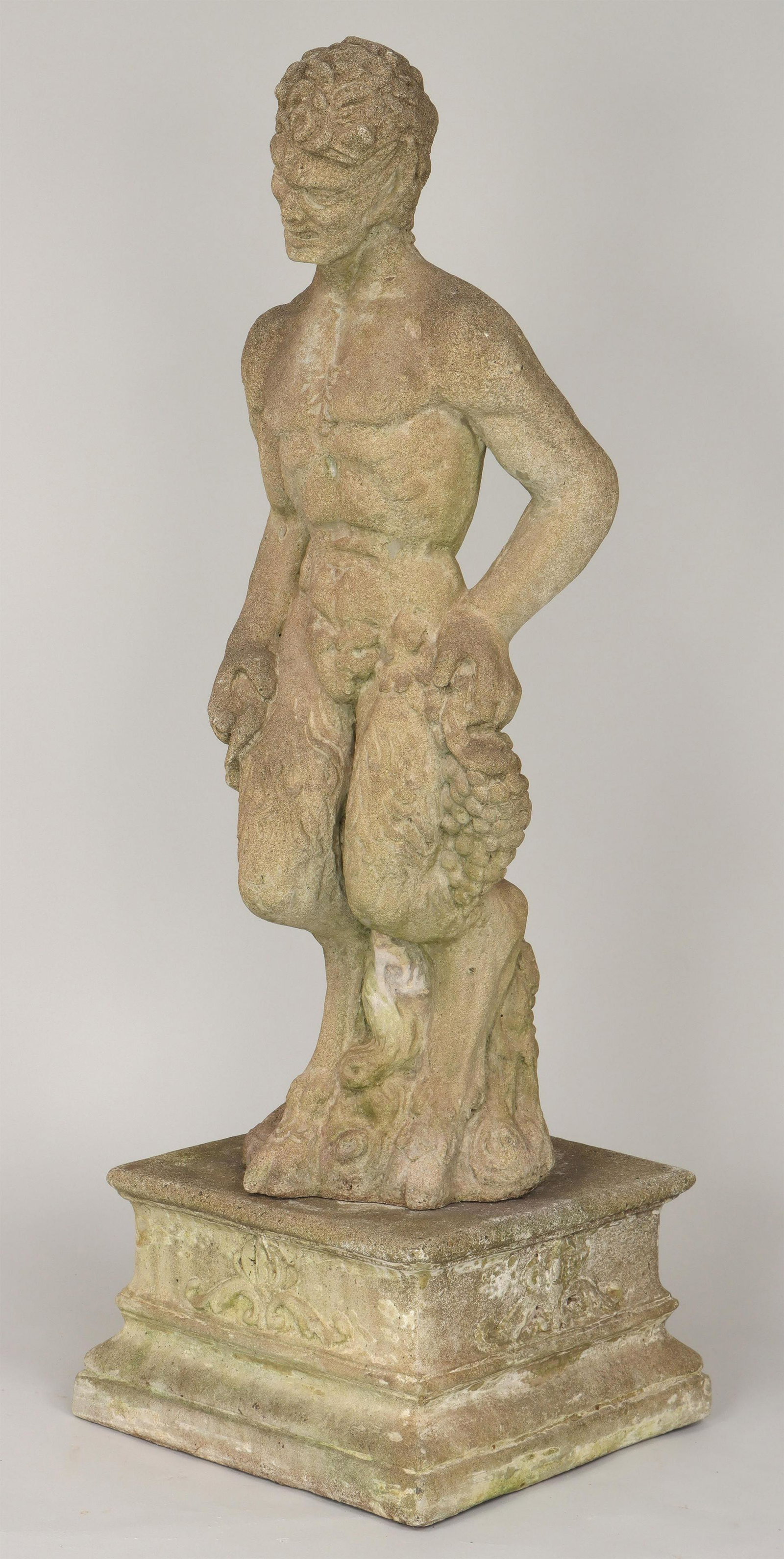 Cast stone satyr garden statue: Cast stone satyr garden statue with grapes, set on a square plinth with foliate relief decoration. Weathered, minor loss to one hoof. 50''h overall. IMPORTANT SHIPPING INFORMATION 1 - LIVE-SHIPPING : 