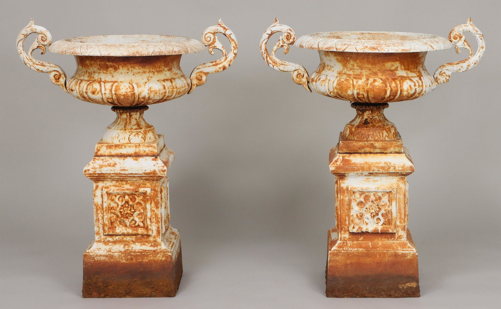 Pair of cast iron two handled urns: Pair of cast iron two handled urns set on pedestals. Weathering and surface rust, handles missing some bolts. 41''h, 34''w, 24''dia. IMPORTANT SHIPPING INFORMATION 1 - LIVE-SHIPPING : The service is p