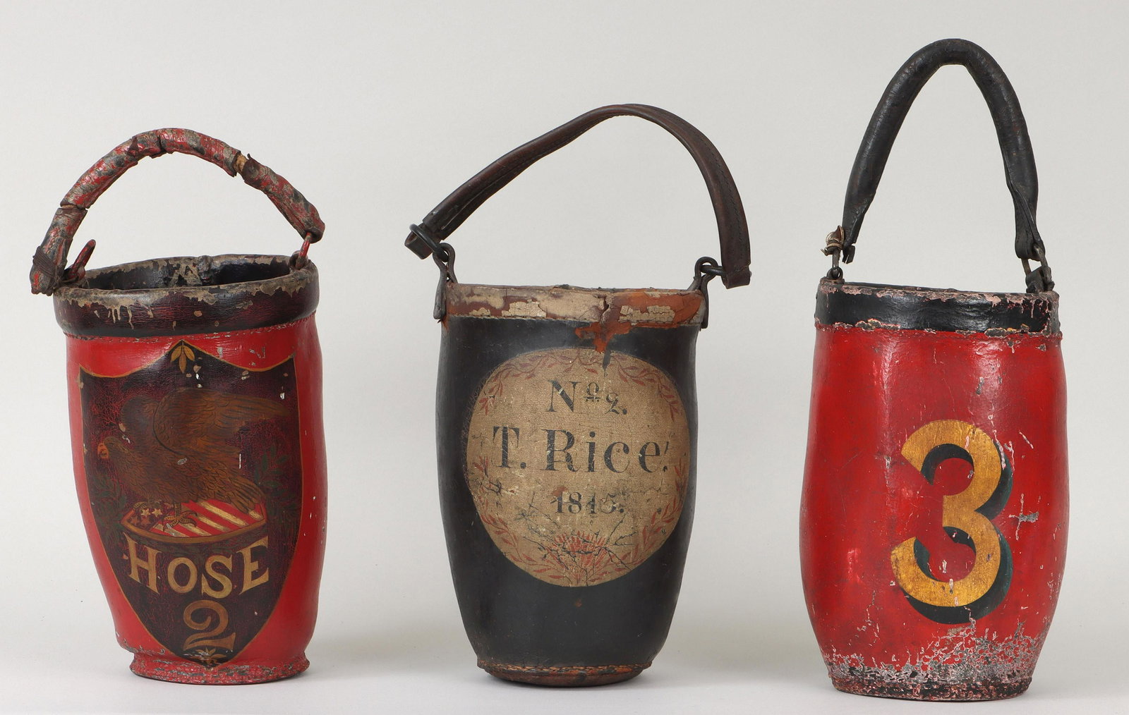 Group of (3) painted leather fire buckets: Group of (3) painted leather fire buckets, with articulated handles, to include: bucket depicting eagle on an American flag shield, marked ''Hose 2''; 19th century bucket marked ''No. 2 T. Rice'' and