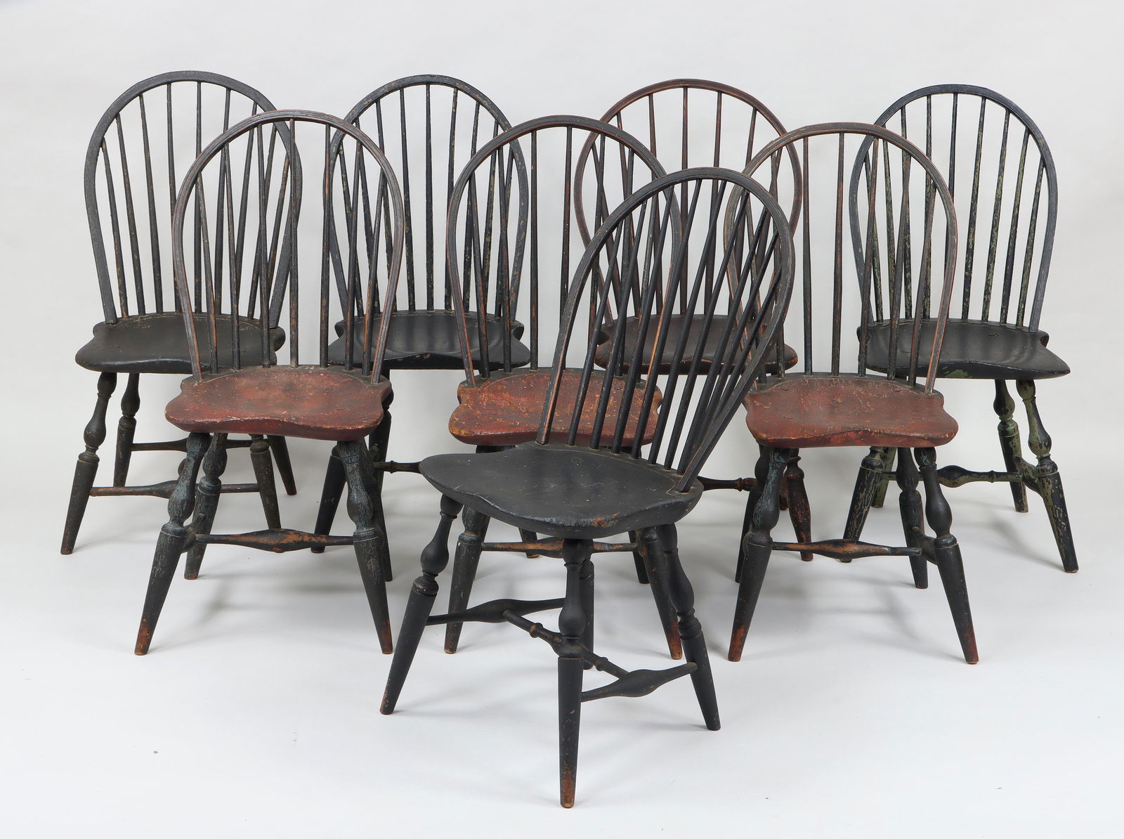 18th/19th century American bowback Windsor chairs: Assembled set of (8) 18th/19th century American black-painted bowback Windsor side chairs, to include: set of (3) with red-stained seats; a pair; along with (3) similar individual chairs. Paint loss,