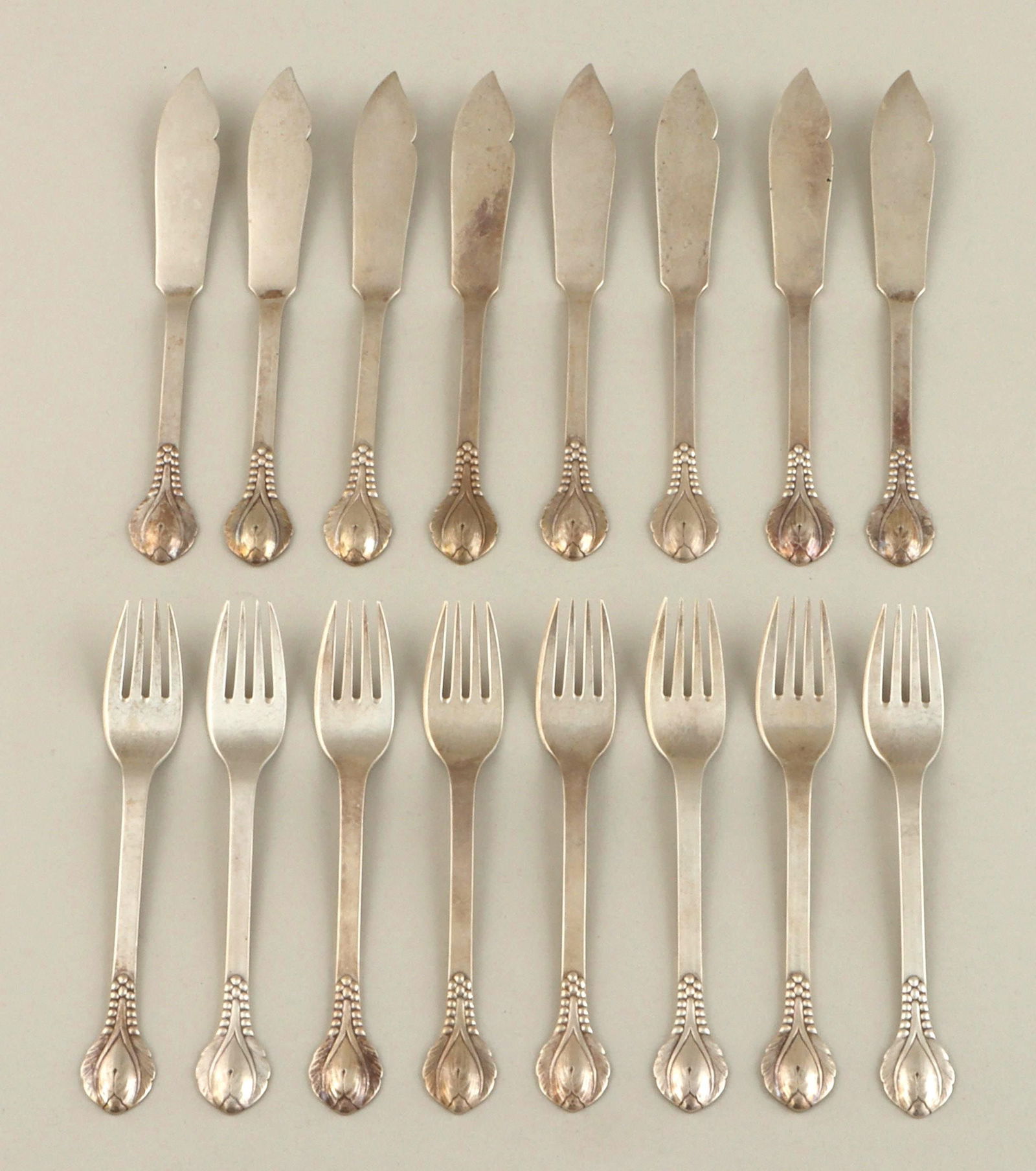 Danish sterling fish flatware set: Danish sterling silver sixteen-piece fish flatware set, Evald Nielsen, in pattern with flower bud and beading, to include: (8) forks; and (8) knives. Marked. Minor wear from use, two knives with spots