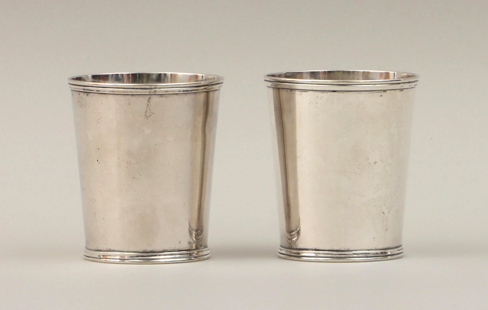 Kentucky and Ohio coin julep cups: Assembled pair of 19th century American Midwest coin silver julep cups, one by D.P. Armer, Richmond, Kentucky, the other by Duhme & Co., Cincinnati, Ohio. Marked on bottoms. Minor dents and wear. Appr